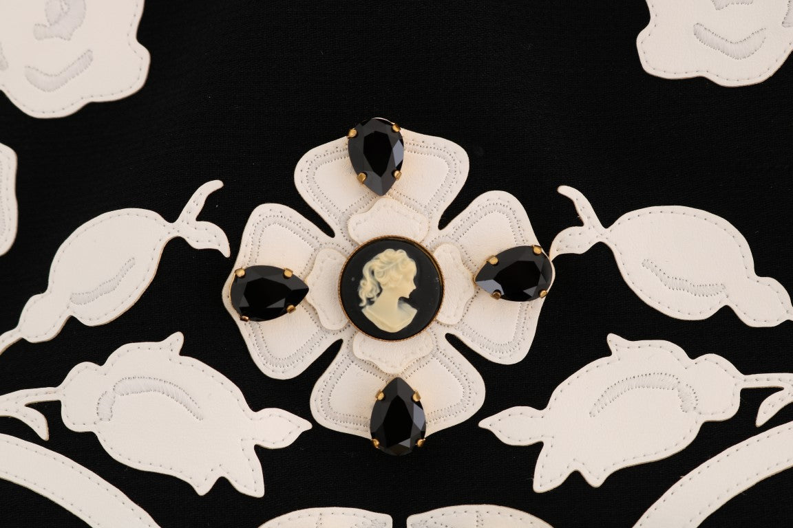 Decorative brooch featuring a central black stone surrounded by smaller stones on a fabric background