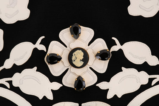 Decorative brooch featuring a central black stone surrounded by smaller stones on a fabric background