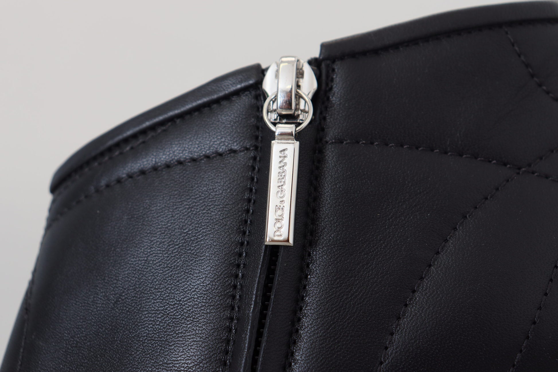 Black leather wallet with silver zipper pull and embossed logo on front