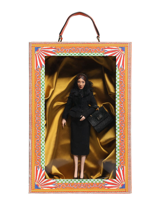 A porcelain doll wearing a black dress with gold accents