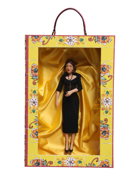 A porcelain doll wearing a black dress with gold accents