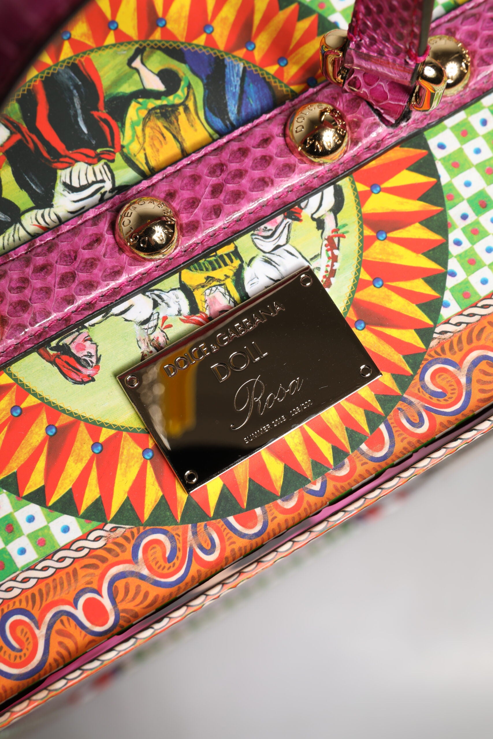 A colorful leather handbag with a ceramic porcelain fashion doll inside