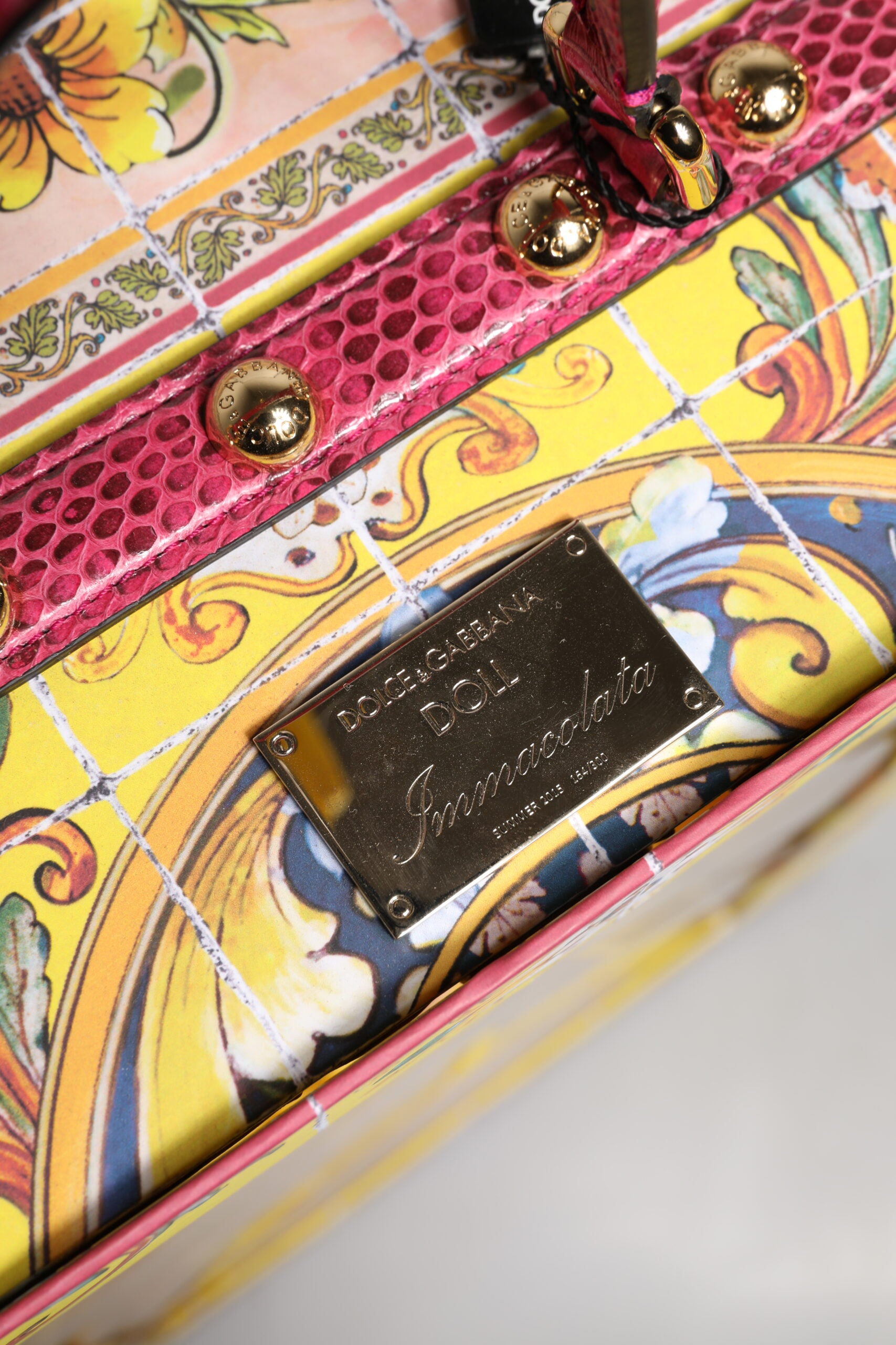 A black dress with a gold label on the front, featuring a floral design and leather straps