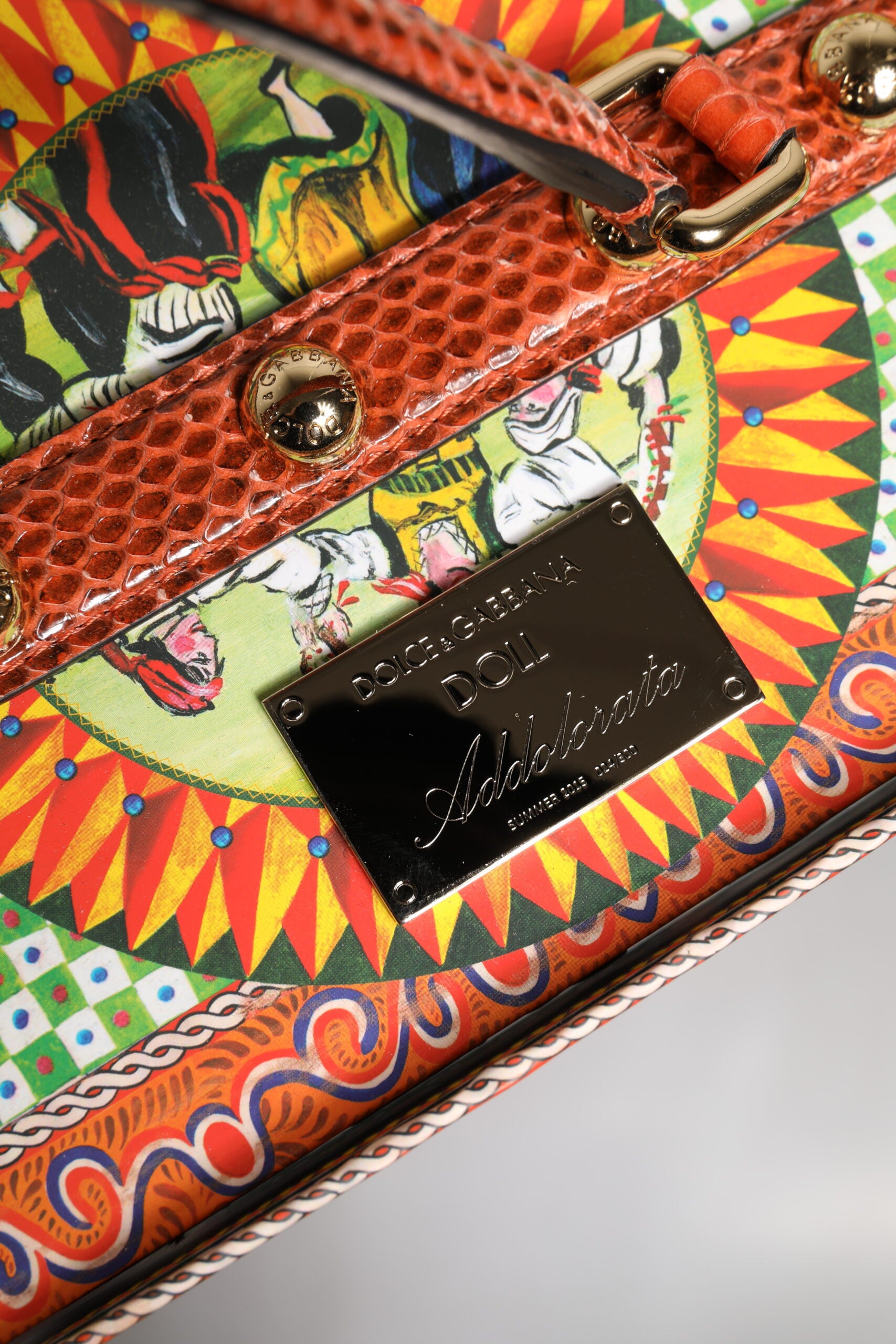 A colorful leather handbag with a cartoonish design, featuring a sunburst pattern and dolls