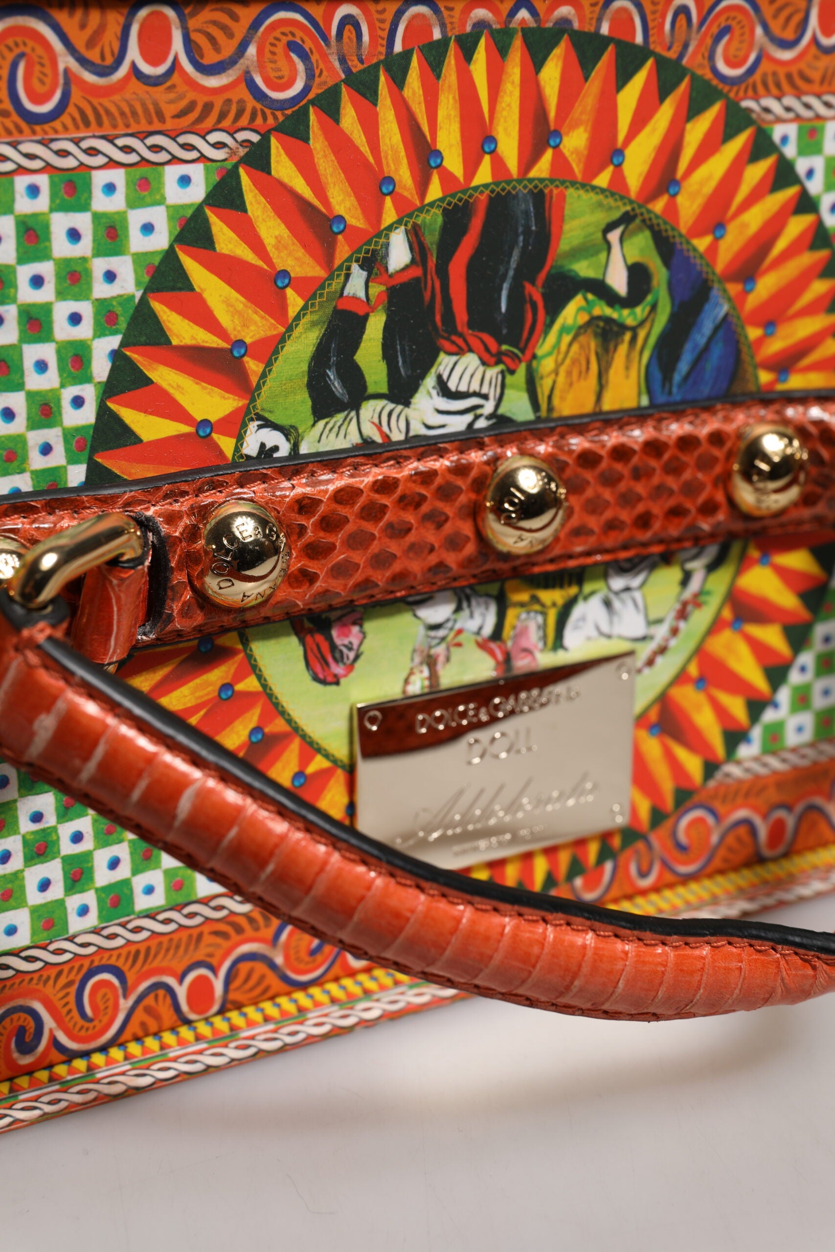 A red leather handbag with gold accents and a colorful design