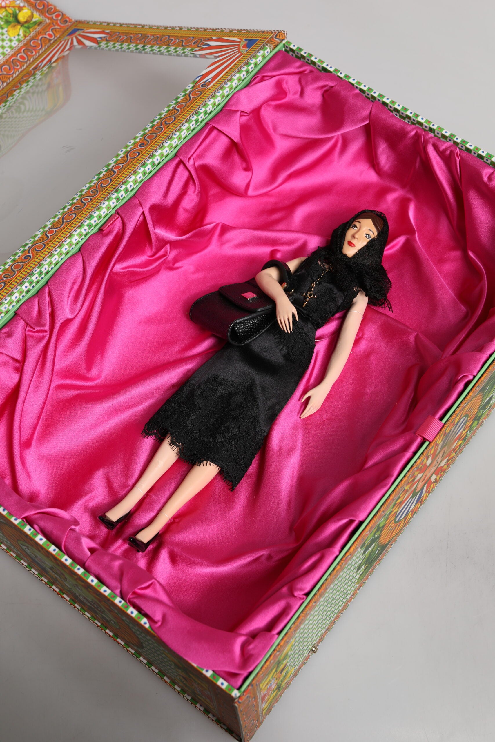 A porcelain doll wearing a black dress with lace detailing
