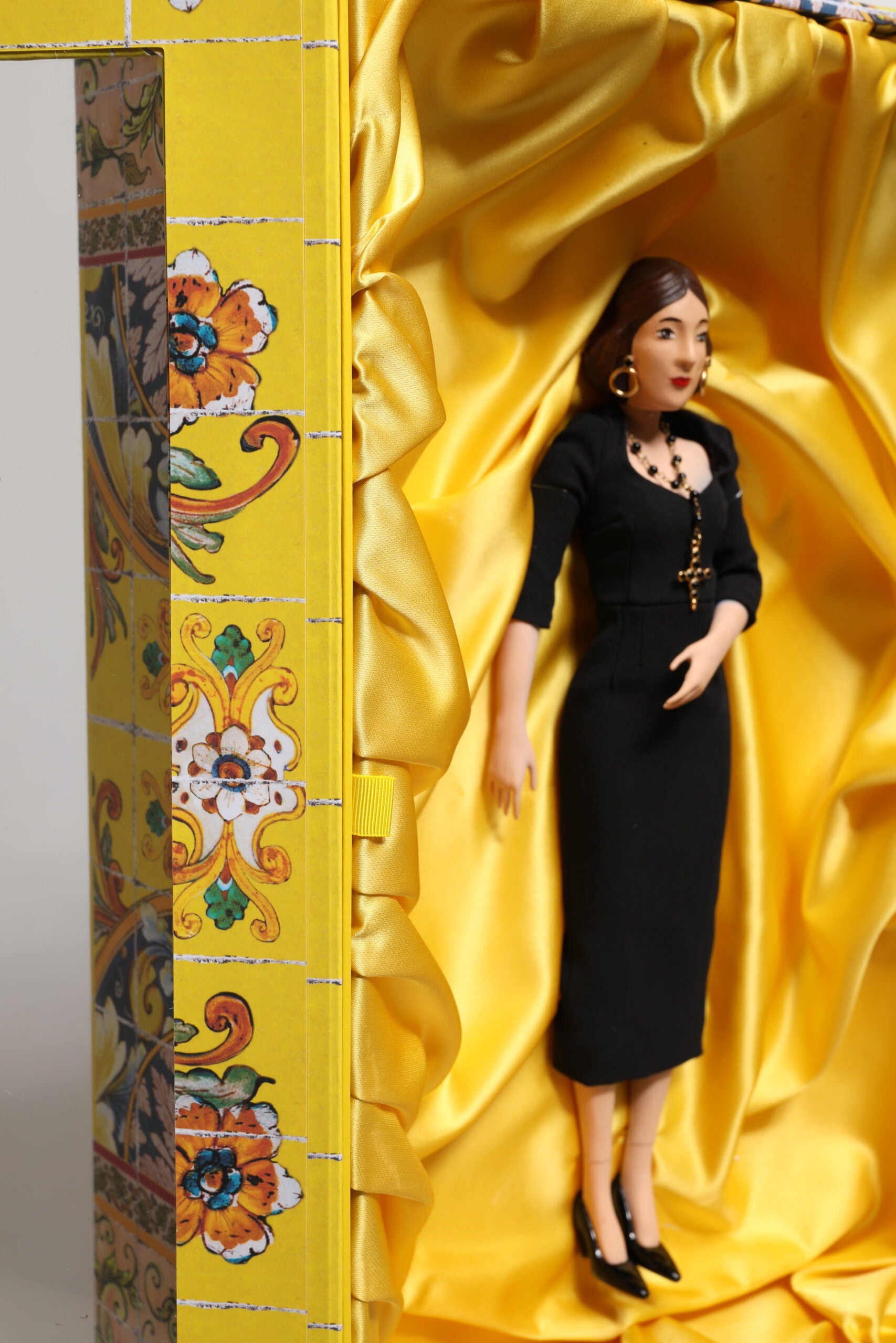 A porcelain doll wearing a black dress with gold accents