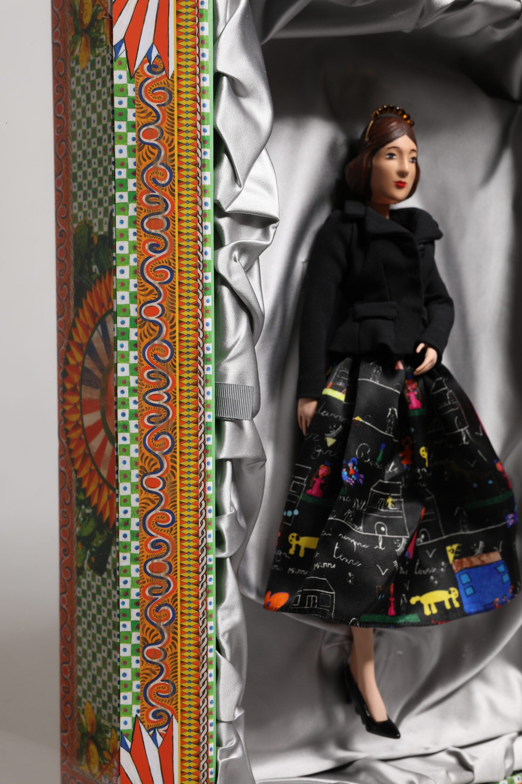 A ceramic porcelain doll wearing a black dress with colorful designs