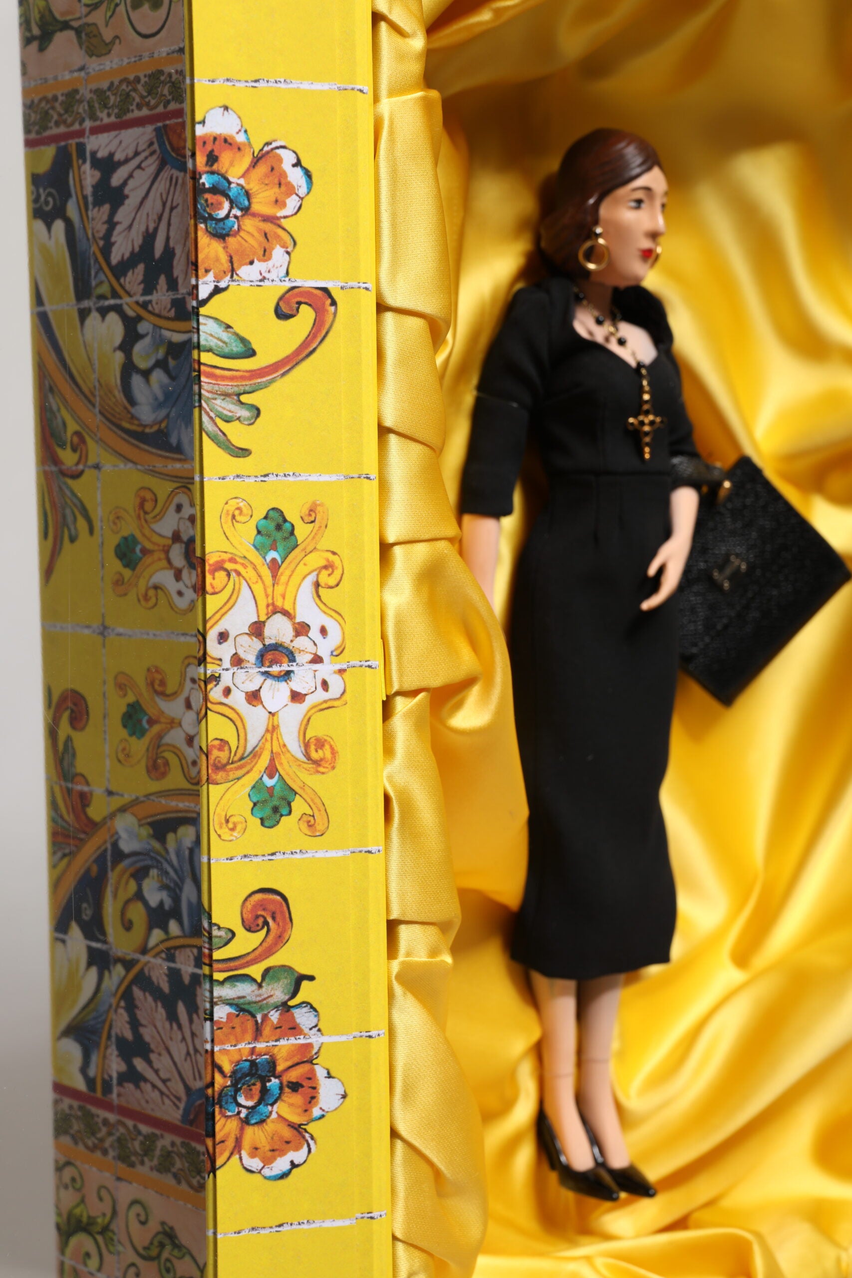 A porcelain doll wearing a black dress with gold accents
