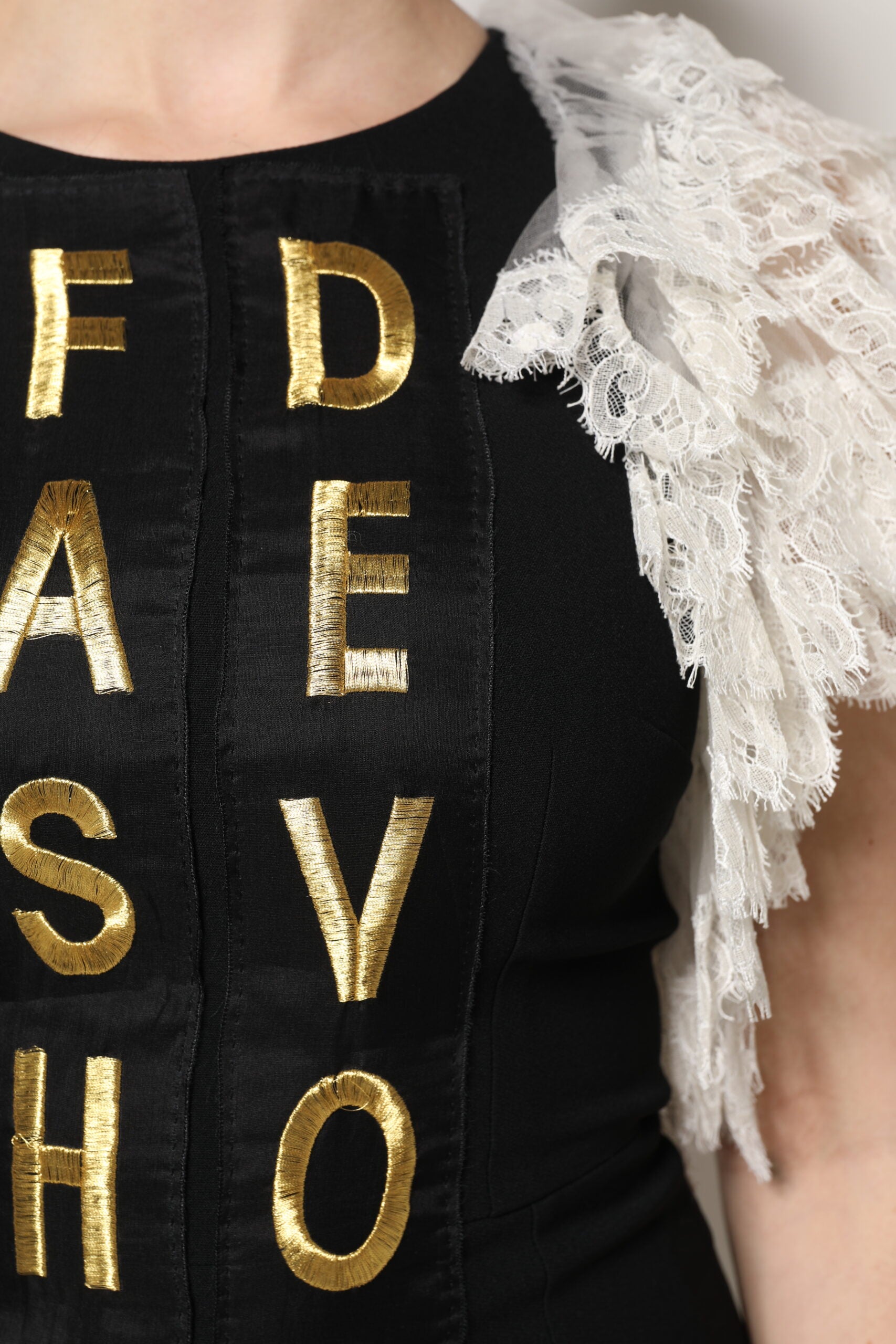 A black embellished mini dress with gold lettering spelling "Fashion Devotion"