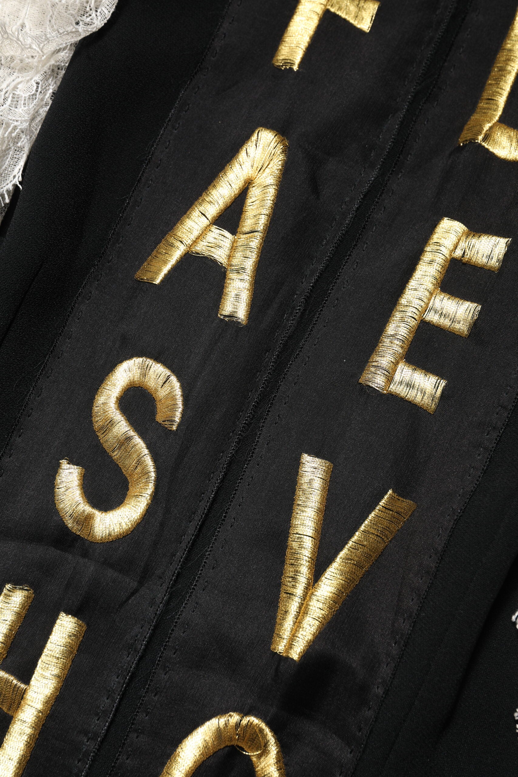 Gold embroidered lettering on black fabric of a mini dress