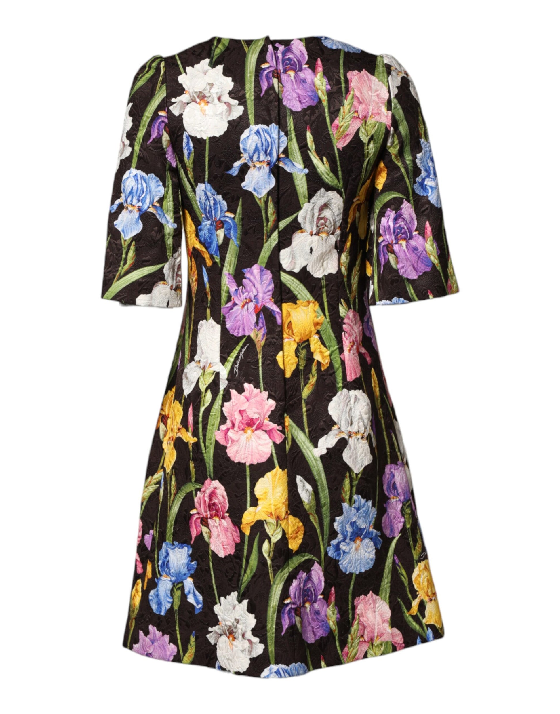 A black floral brocade dress with an A-line silhouette. It features a vibrant pattern of flowers and leaves