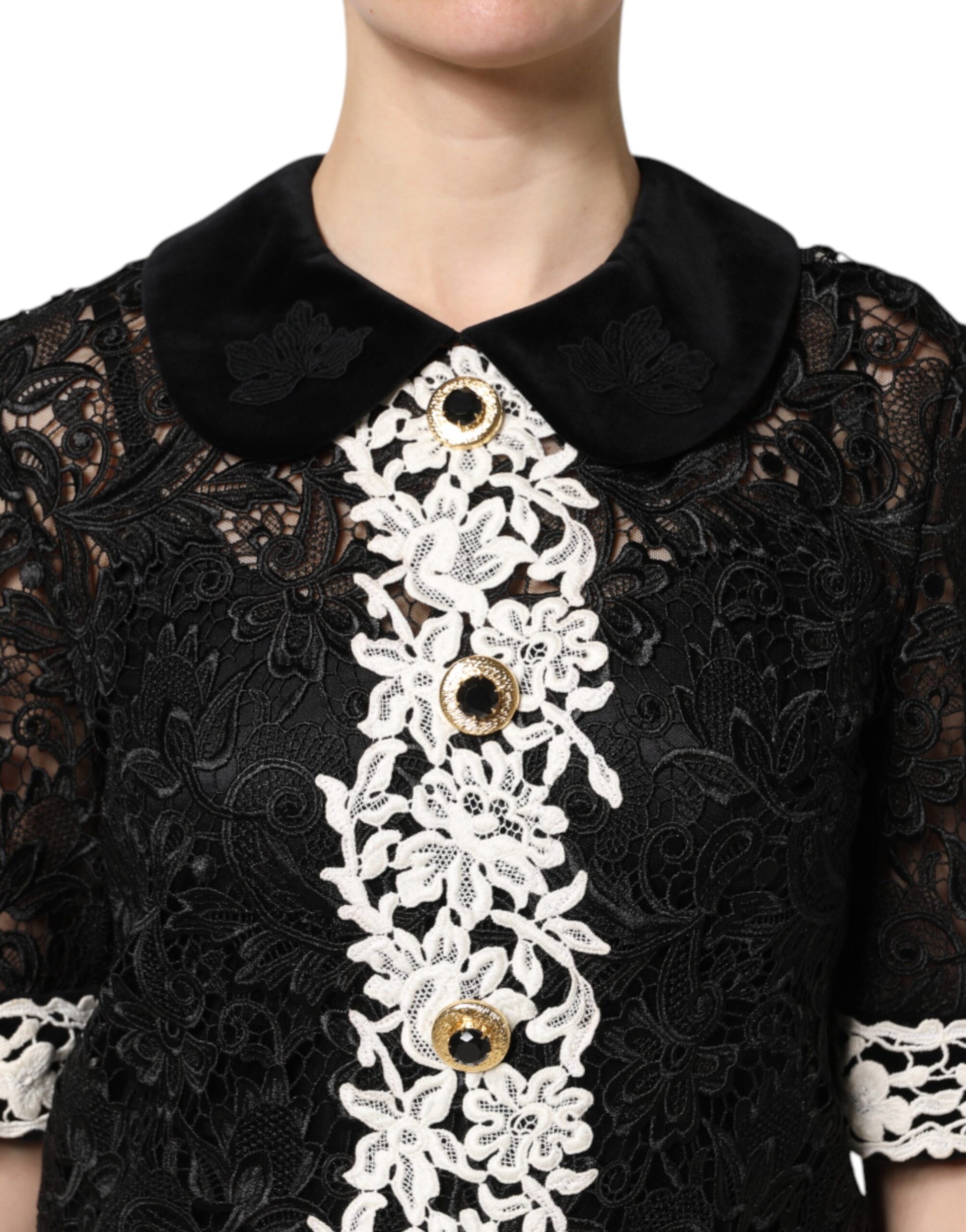 A black lace dress with floral embellishments and gold buttons on the front