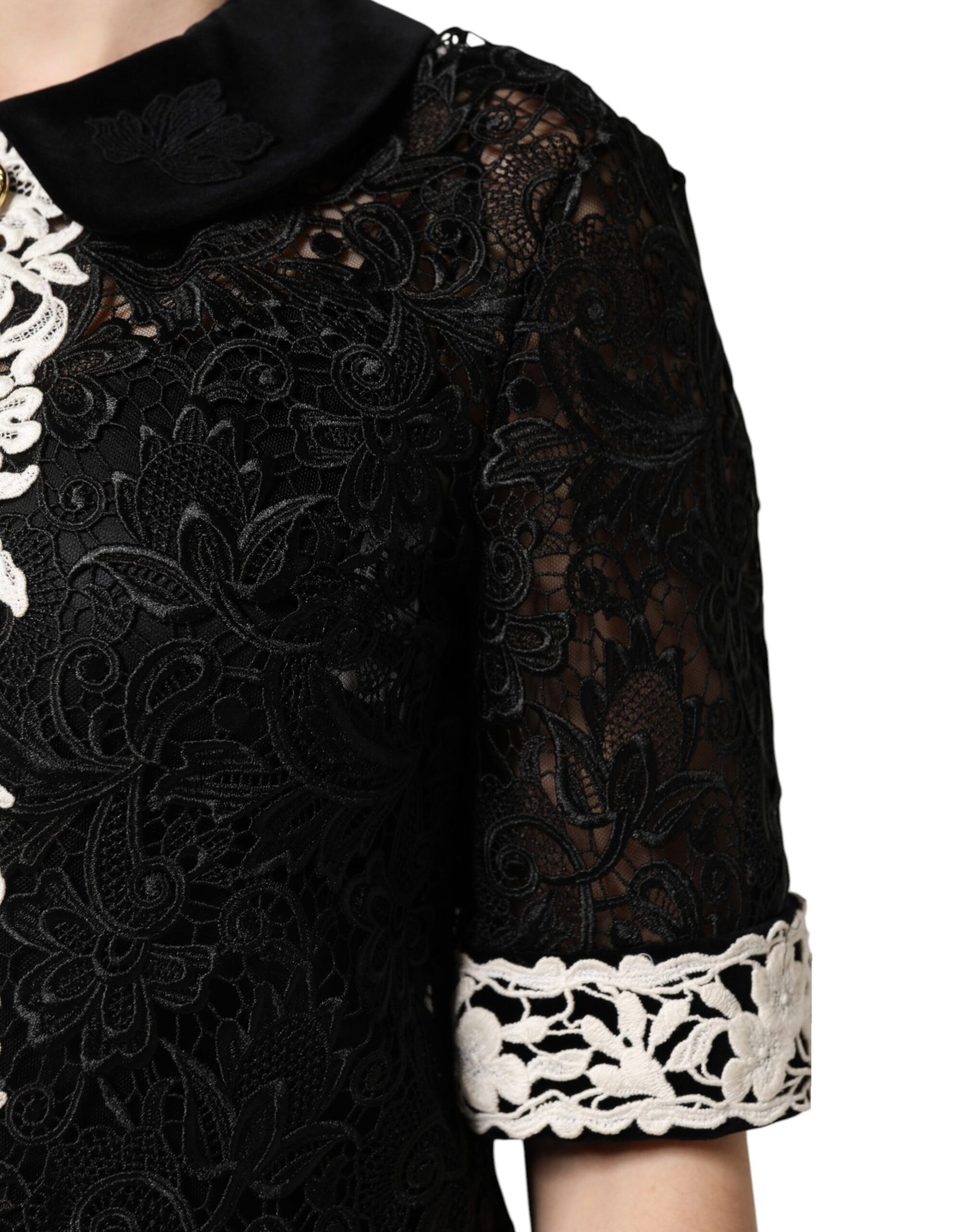 A black lace dress with floral embellishments and white trim on the sleeves