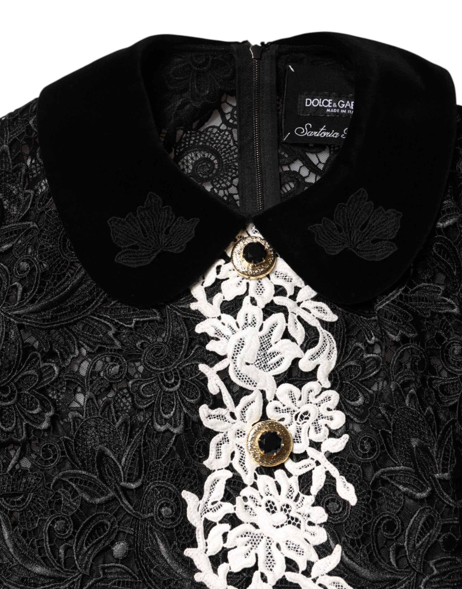 A black lace dress with floral embellishments and gold buttons