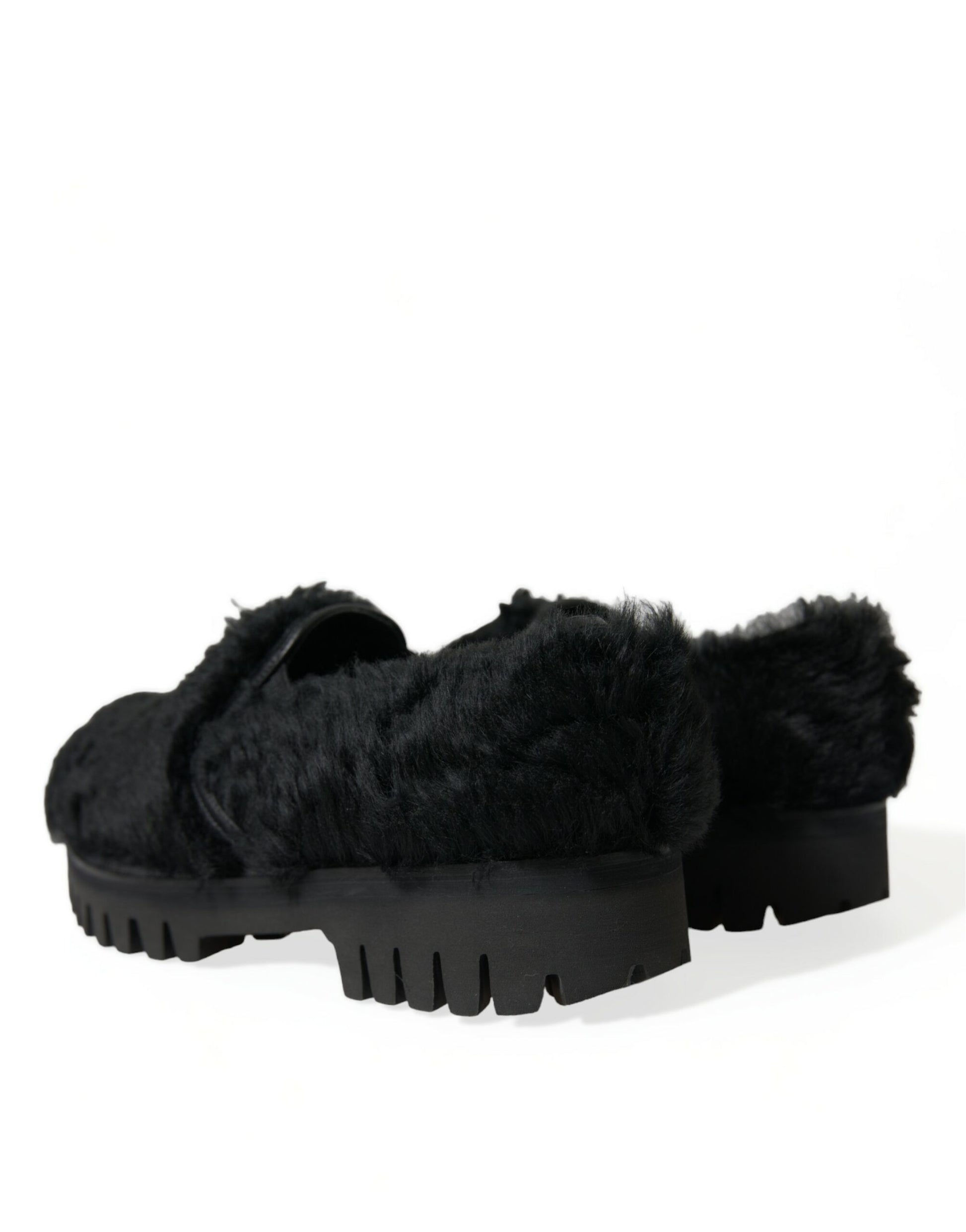 Pair of black furry slippers with a thick sole and a distinctive design on top