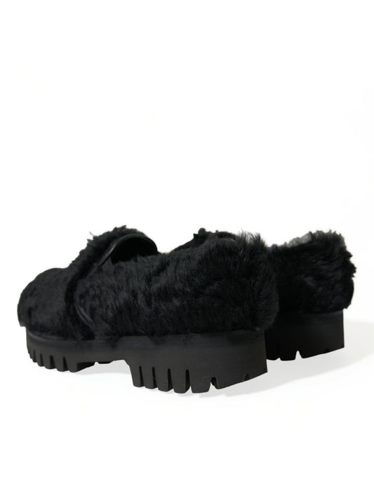 Pair of black furry slippers with a thick sole and a distinctive design on top