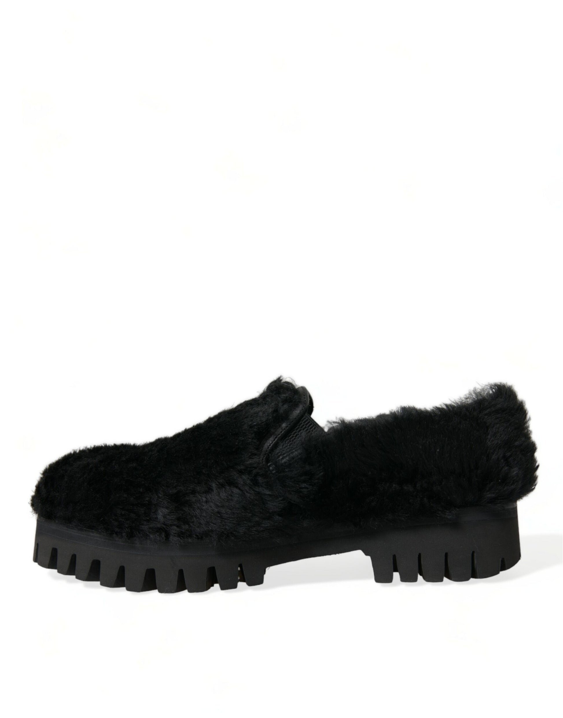Pair of black furry slippers with a thick sole and a raised platform on the back