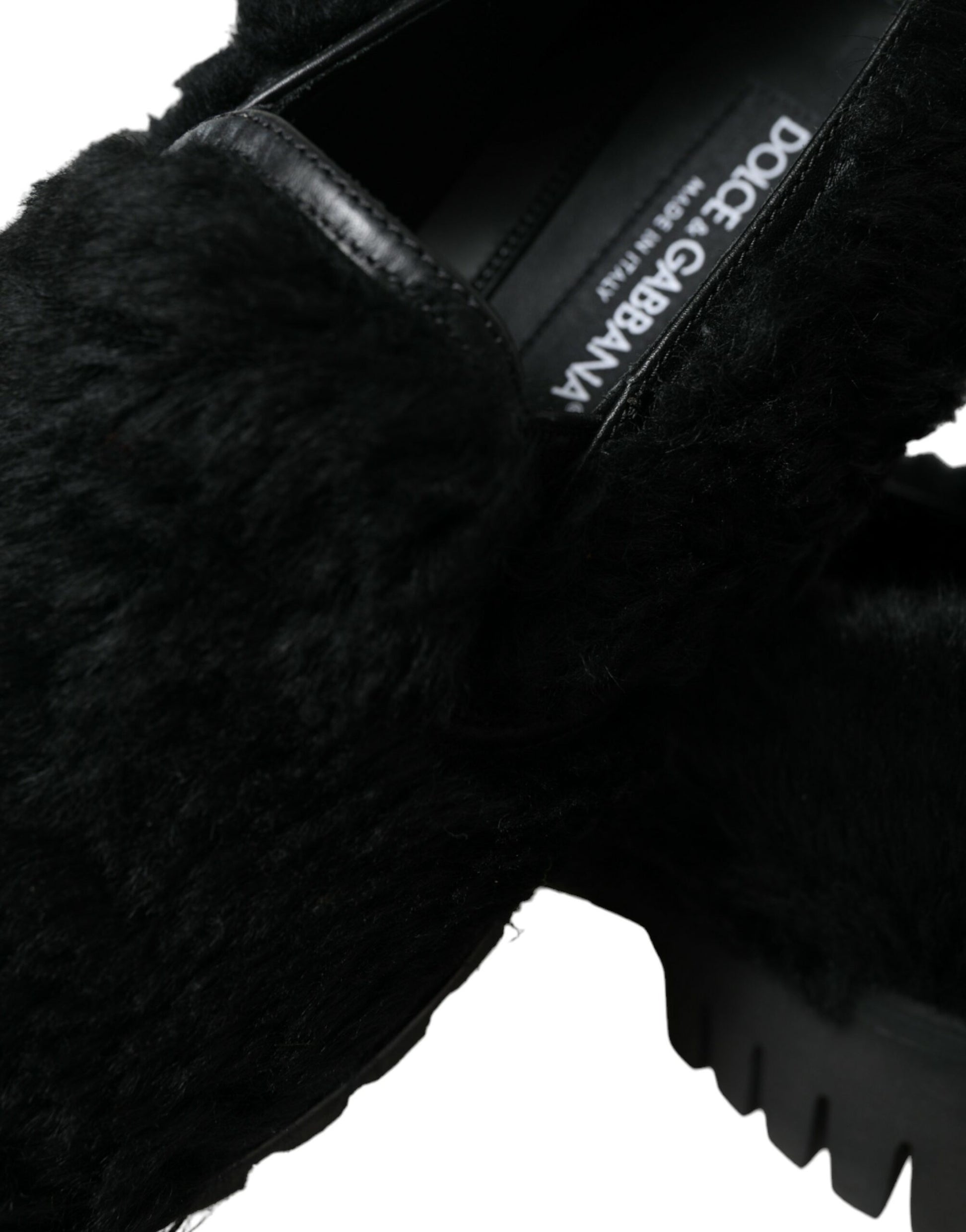 Furry black slipper with white label on side