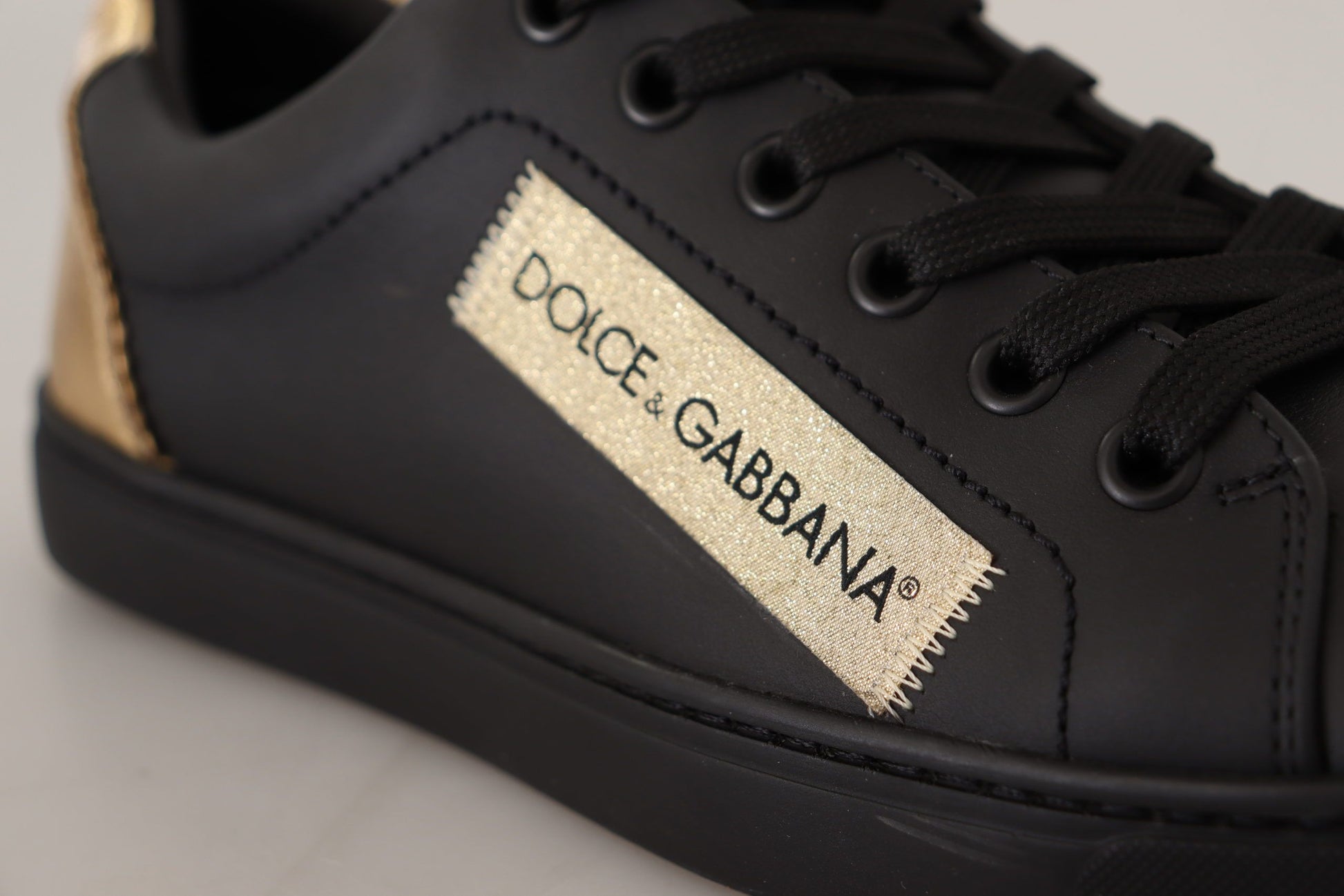 Black sneaker with gold accents and a label that reads dolce & gabbana