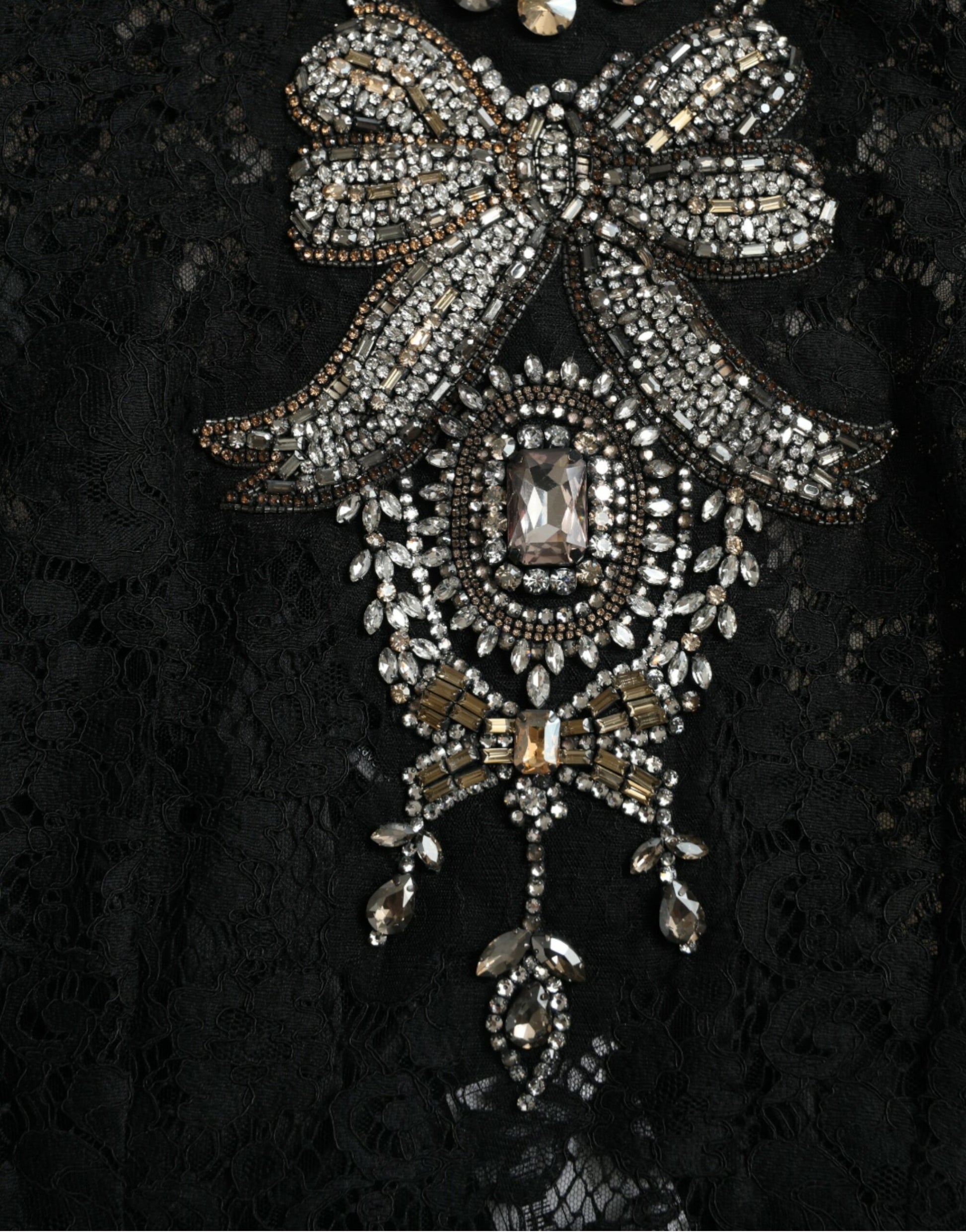 A black lace dress with crystal embellishments and a bow on the front