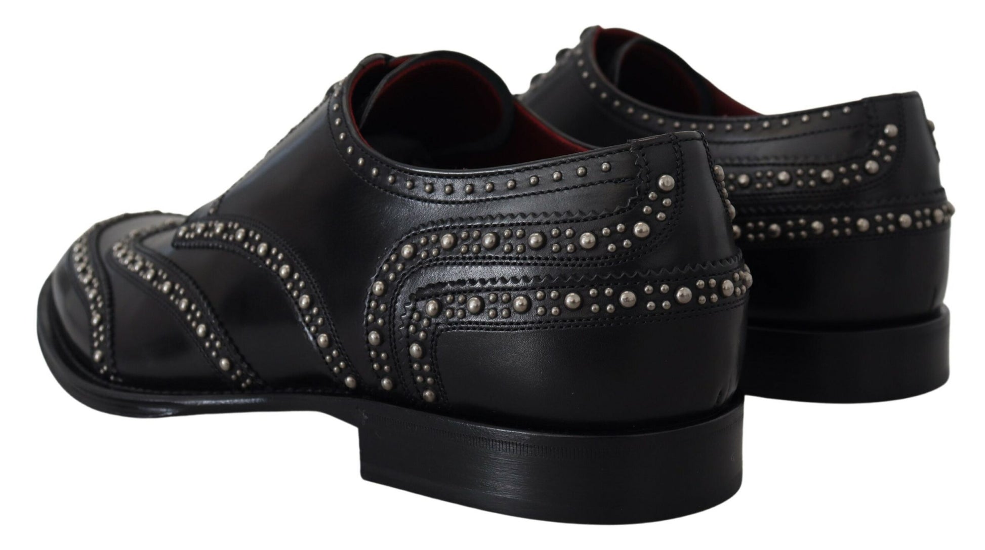 A pair of black leather shoes with studs, featuring a derby design and a strap across the top