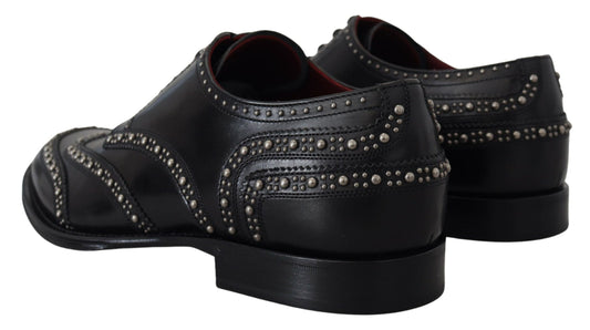 A pair of black leather shoes with studs, featuring a derby design and a strap across the top
