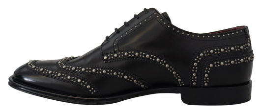 A pair of black leather derby shoes with studs and a bow tie design on the toe