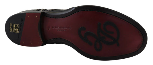 A pair of black leather dress shoes with studs, featuring a red sole and the brand name on the side