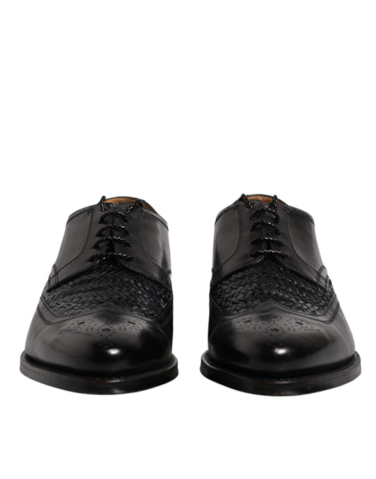 Pair of black leather dress shoes with laces, wingtip design and a shiny finish