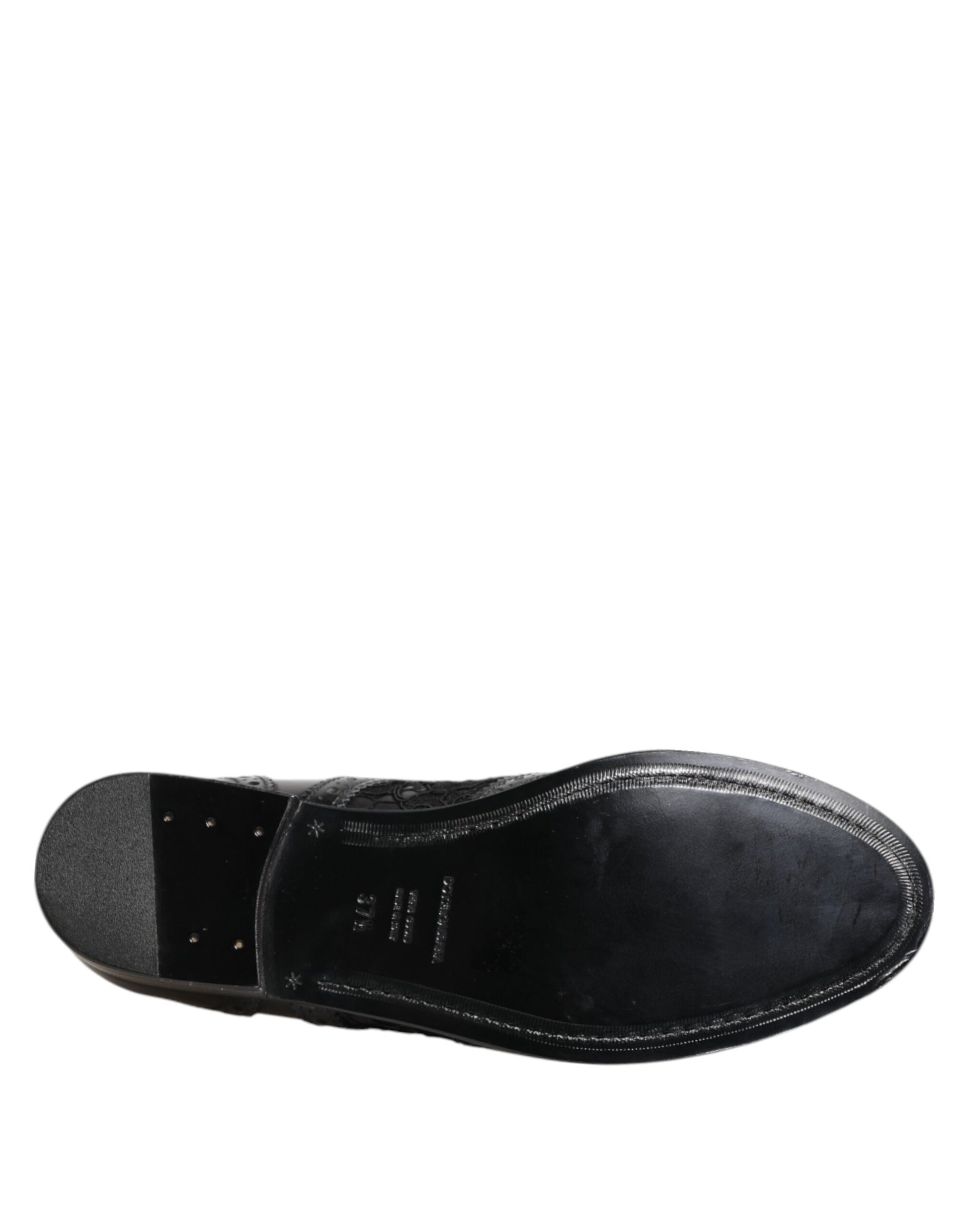 A single black leather shoe with a floral lace design, featuring a low heel and a strap across the top
