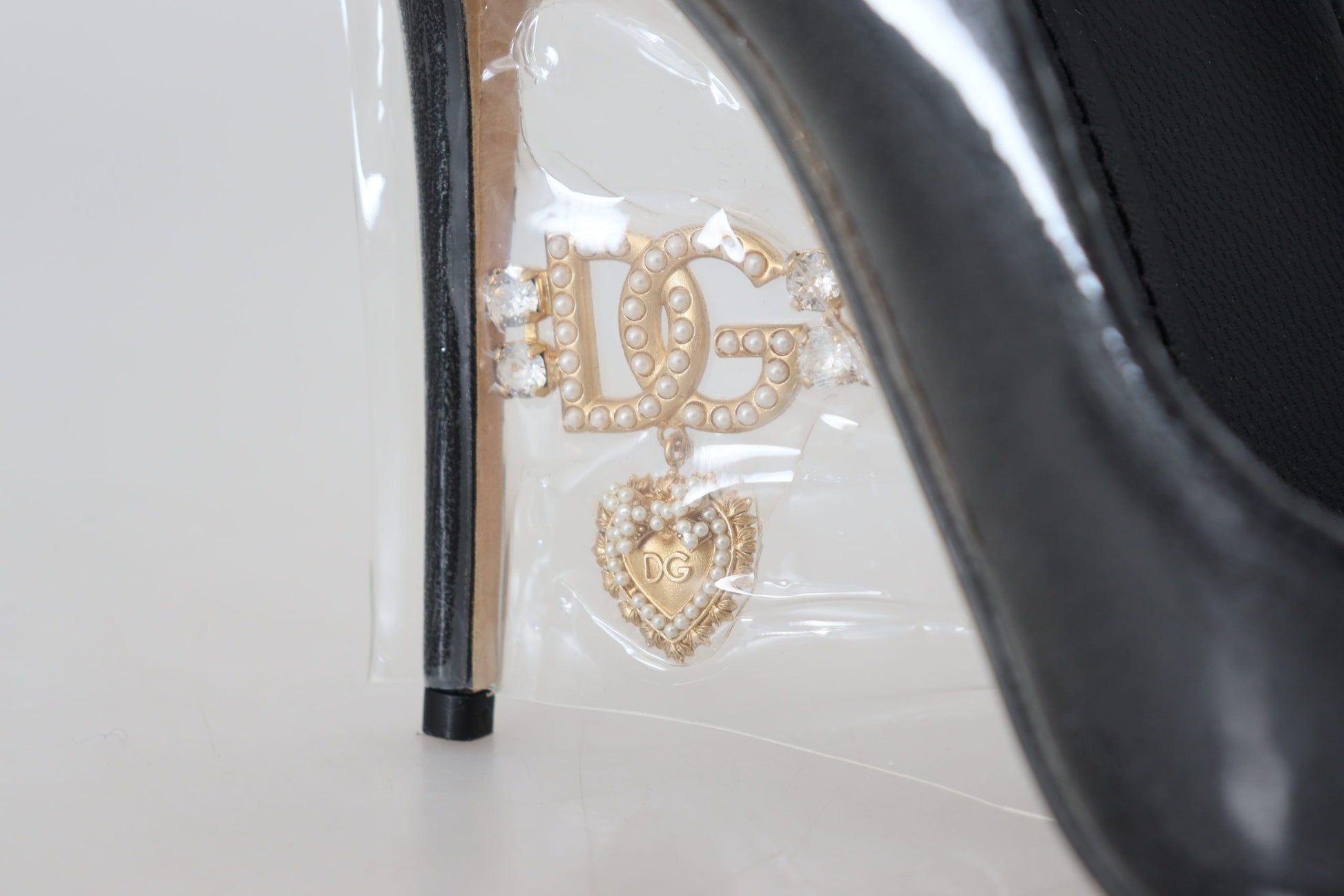 Black high heel shoe with gold embellishments and a heart design on the toe cap