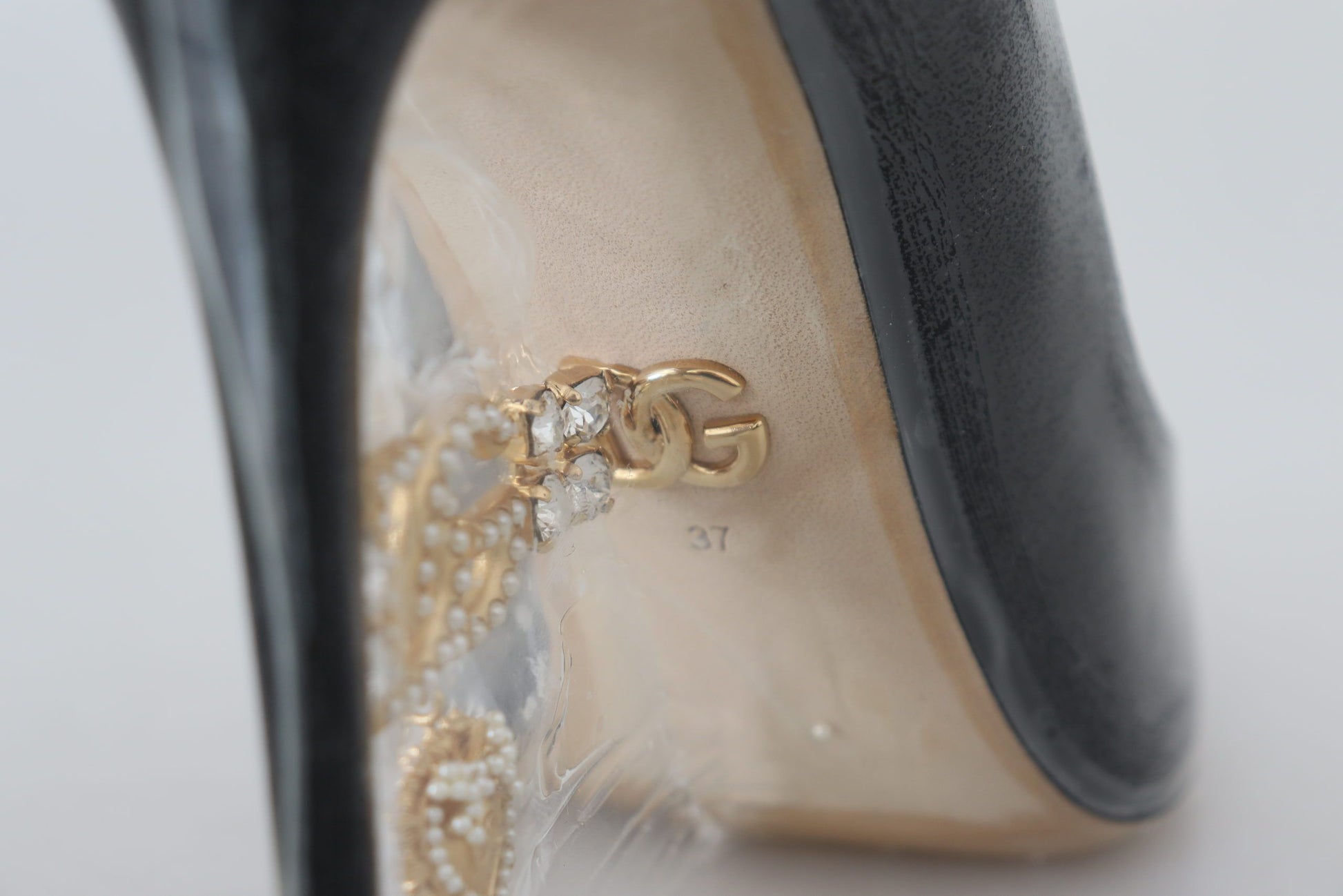 High heel shoe with a gold Gucci logo on the side and a feathered design