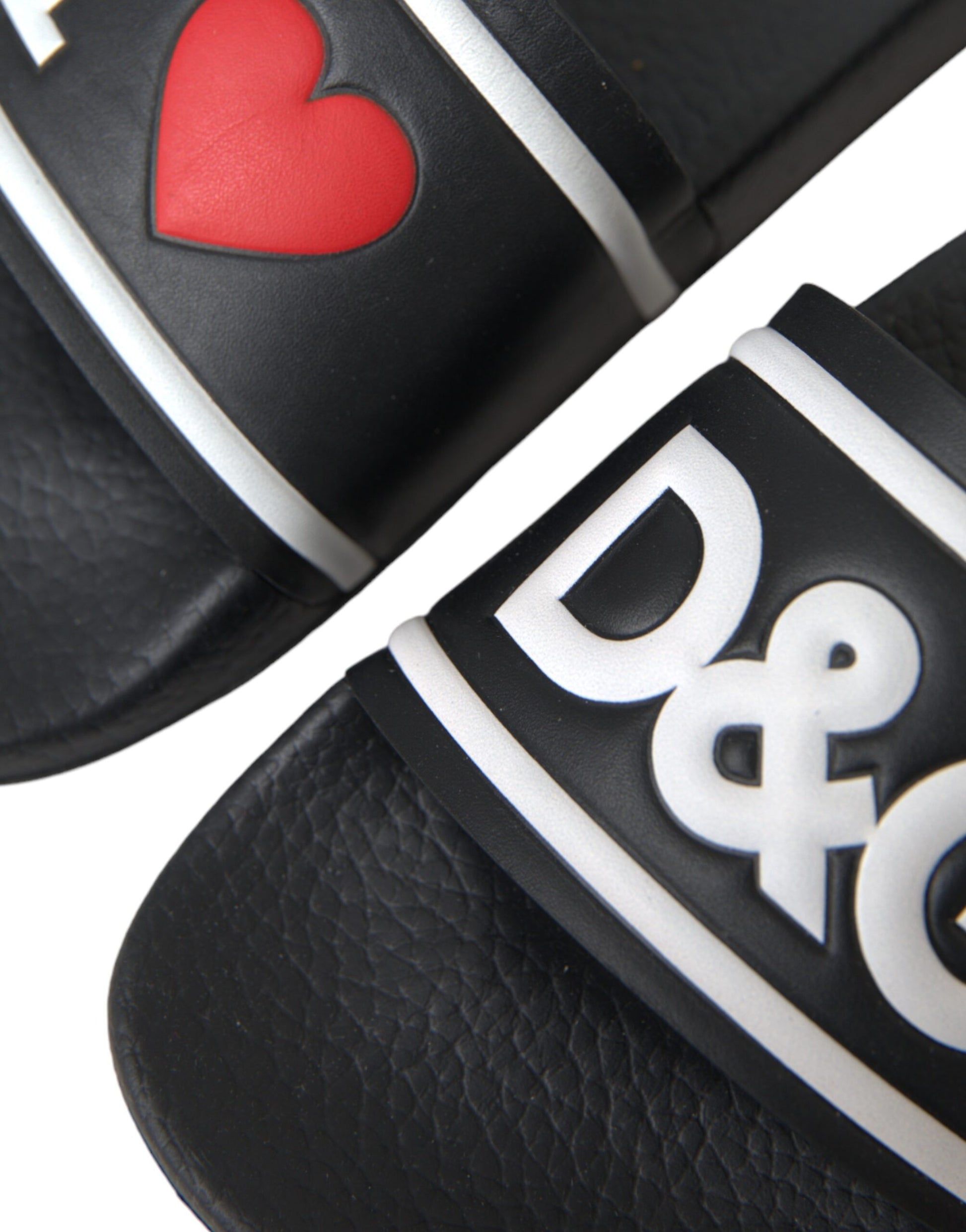 Pair of black flip flops with white lettering and a red heart on the strap