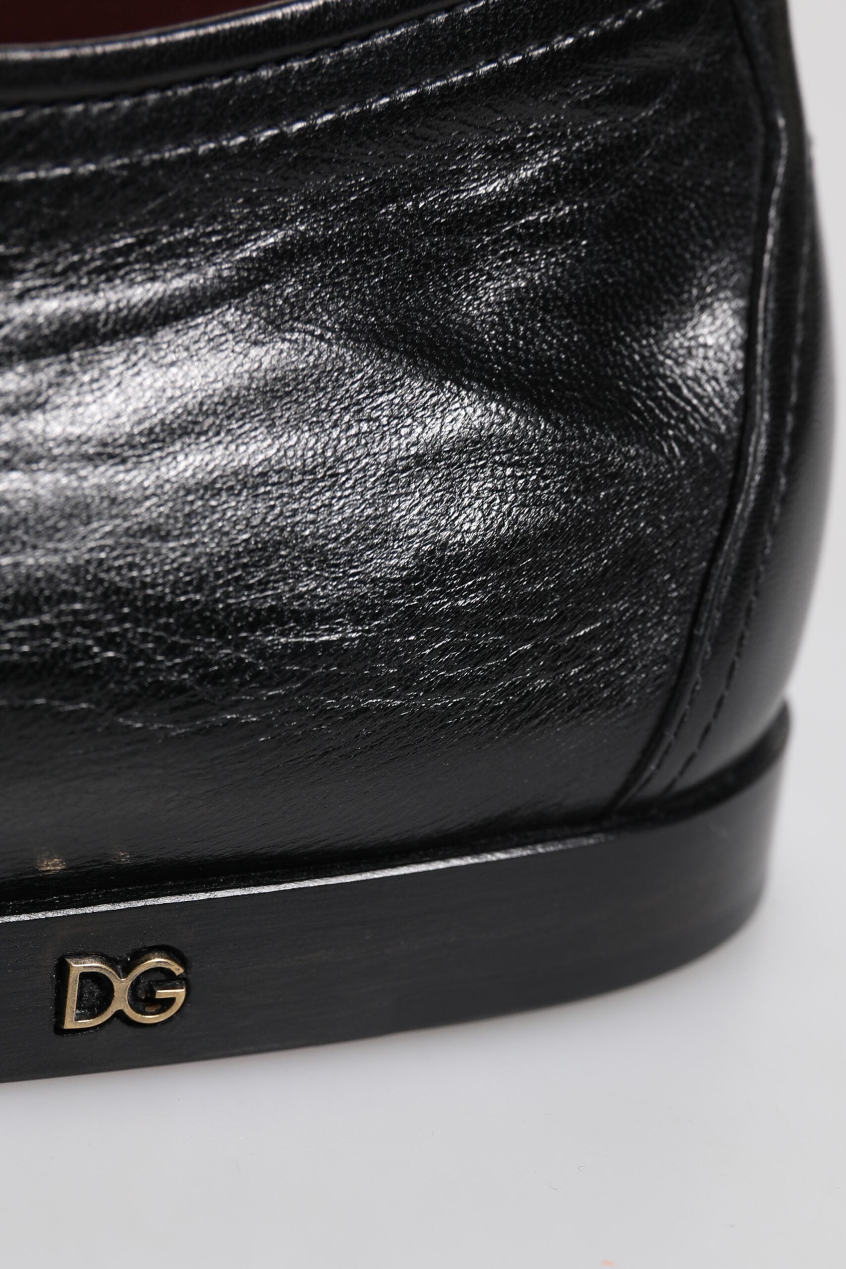 A pair of black leather lace-up dress shoes with a gold logo on the side