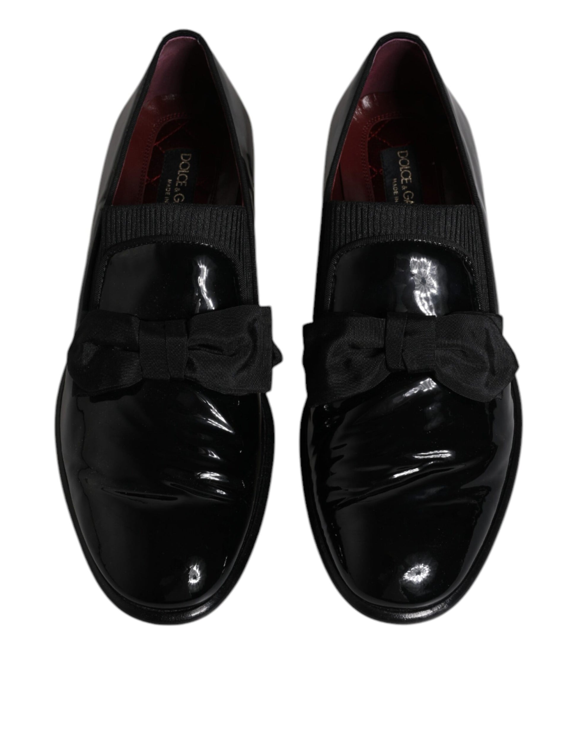 Pair of black leather loafers with red accents, featuring a bow tie design