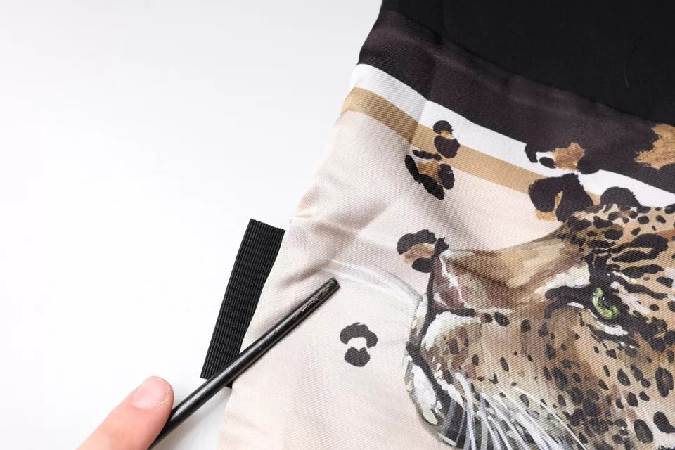 Hand holding a pen over a scarf with a leopard print design