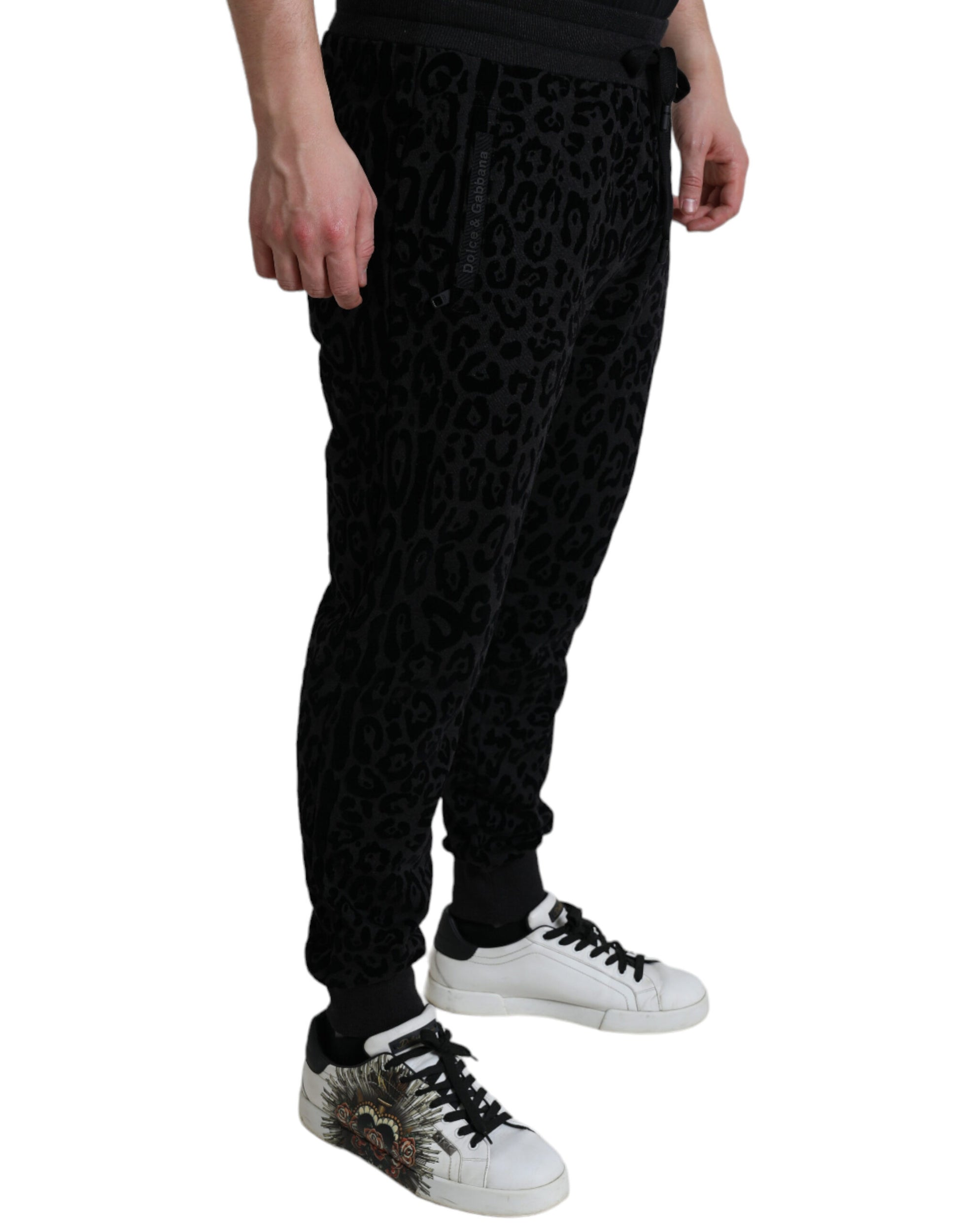 Man wearing black pants with white writing and sneakers