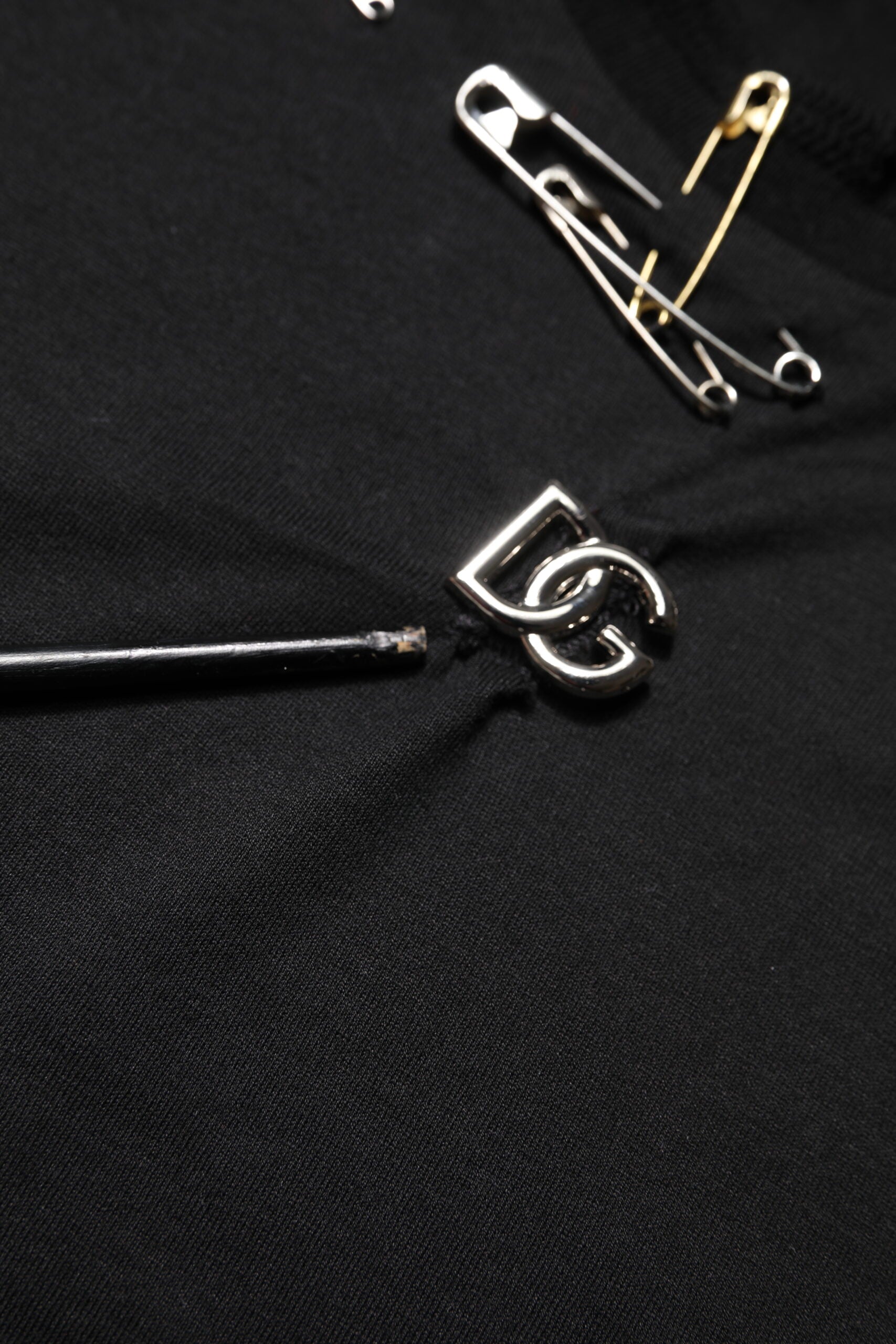 Silver metal pins on black fabric background