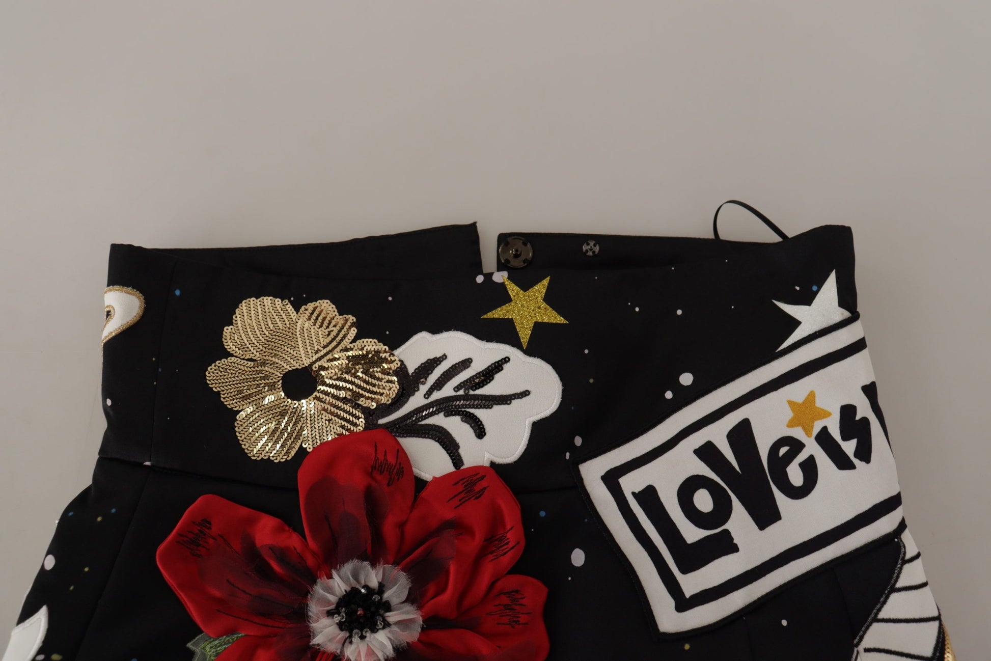 Black jeans with floral embroidery, stars, and a red flower