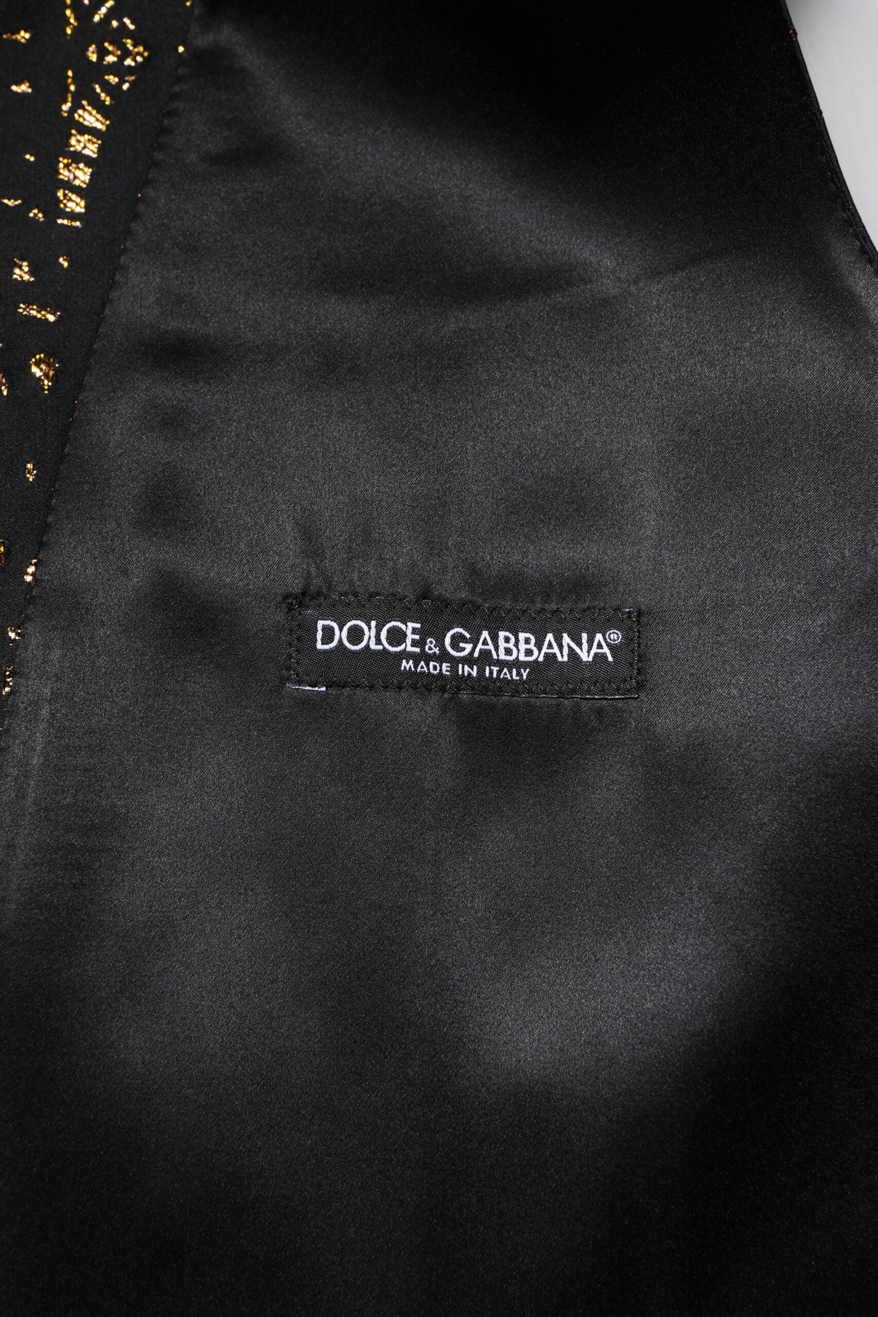 A black lurex waistcoat with a gold logo