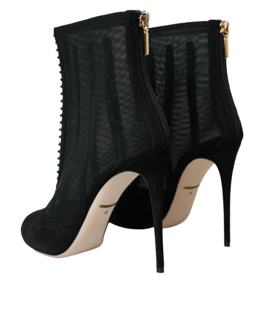 Pair of black high heel boots with gold accents and zippers