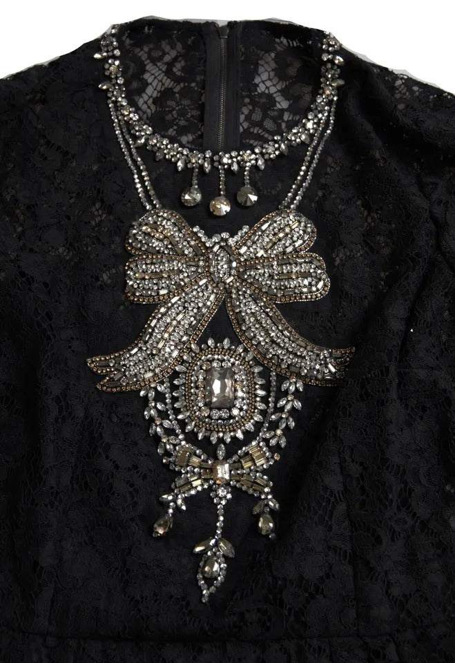 A black nylon lace embellished sheath dress with a large bow and intricate jewelry