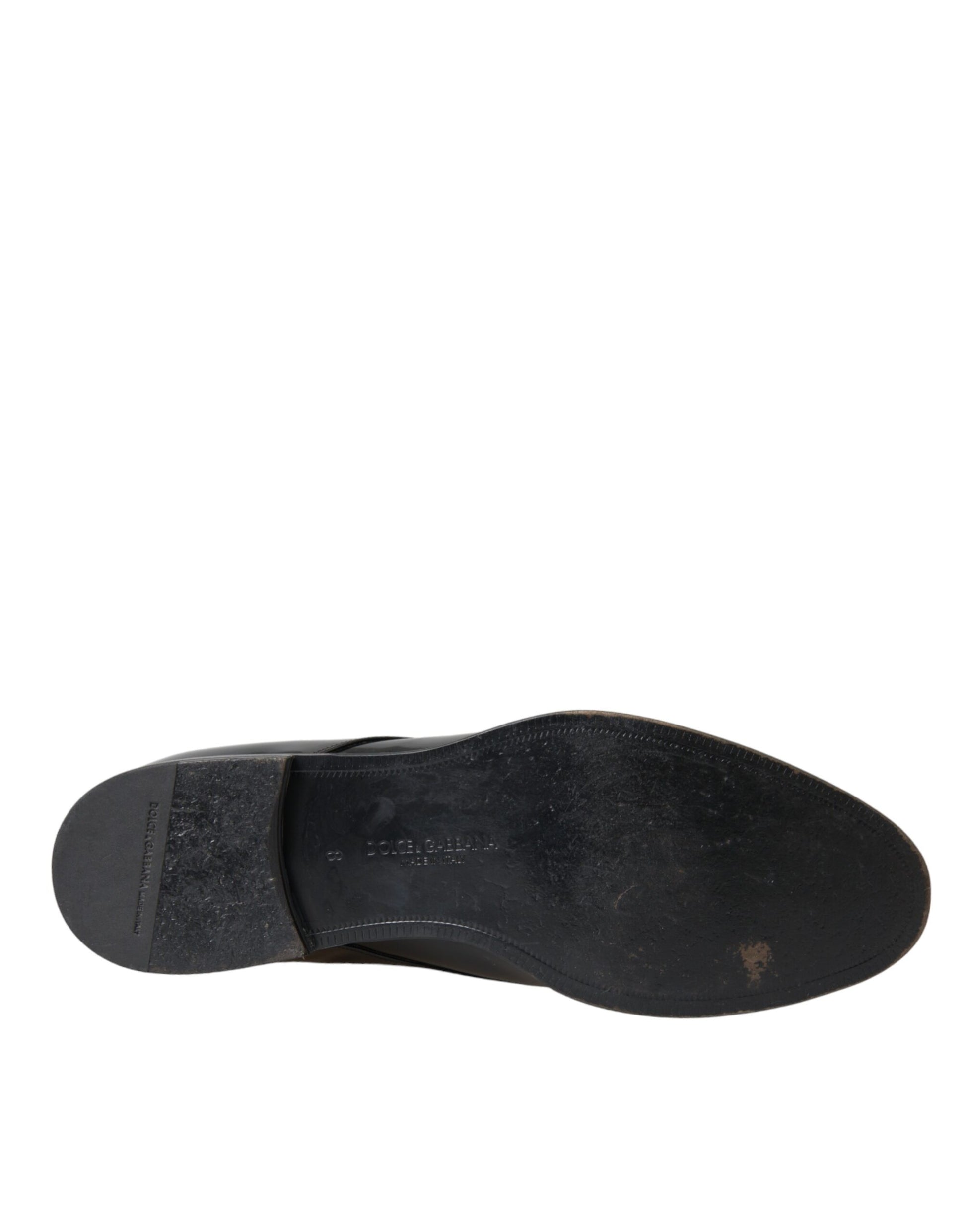 A single black patent leather dress shoe with a strap across the top, featuring a visible logo on the side