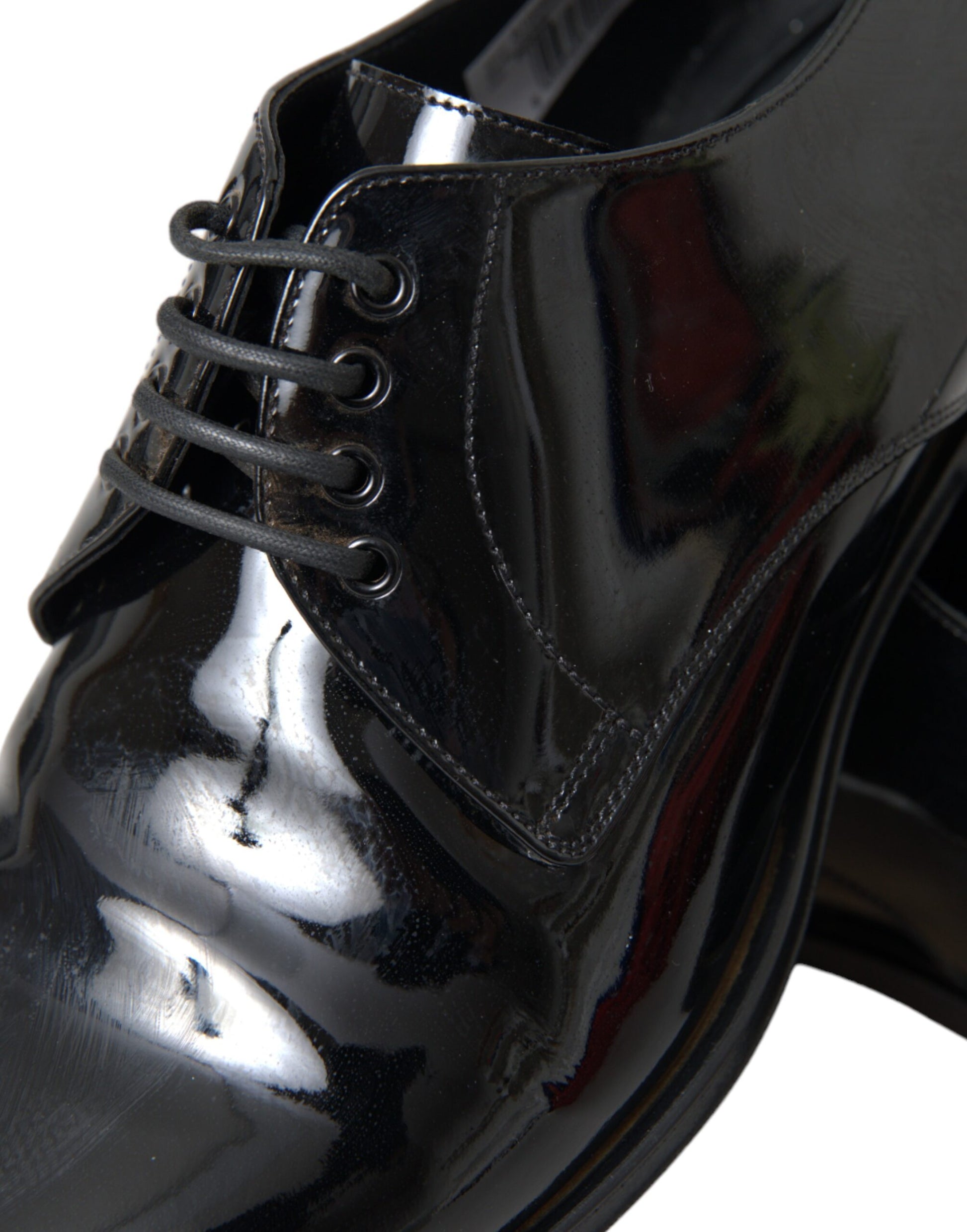 A pair of black patent leather dress shoes with laces and a shiny finish