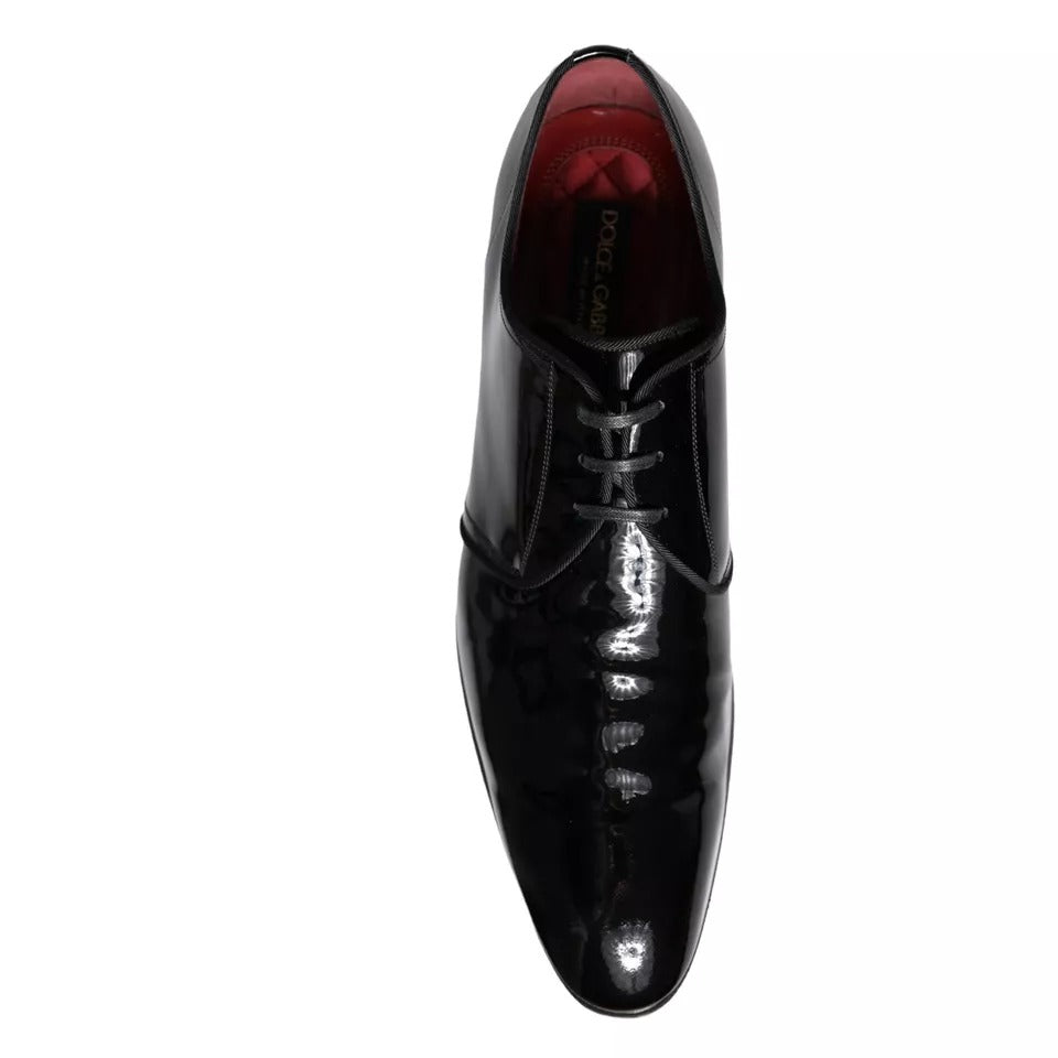 A pair of black patent leather dress shoes with laces and a red lining