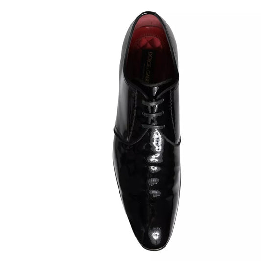 A pair of black patent leather dress shoes with laces and a red lining