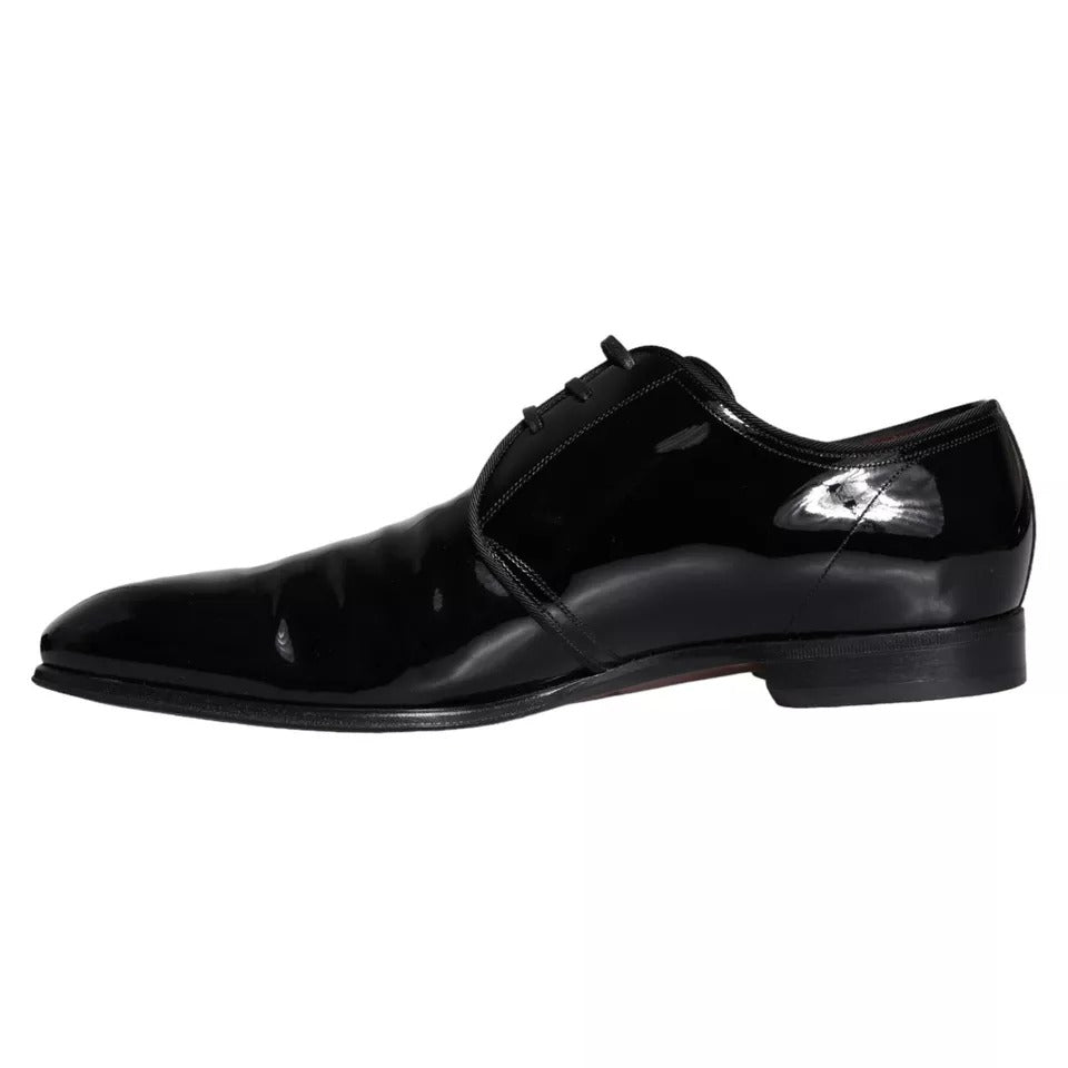 A pair of black patent leather dress shoes with a lace-up design, featuring the Dolce & Gabbana logo on the side