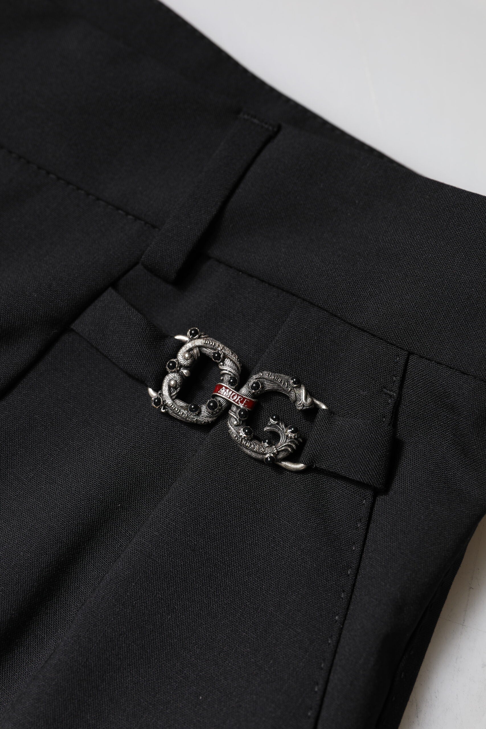 A pair of black polyester high waist dress pants with a silver buckle on the belt loop