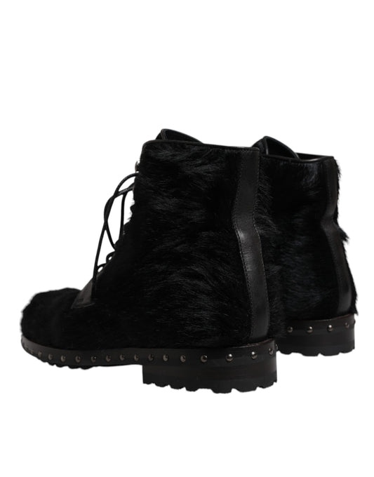 Pair of black fur lined boots with laces and studs on soles